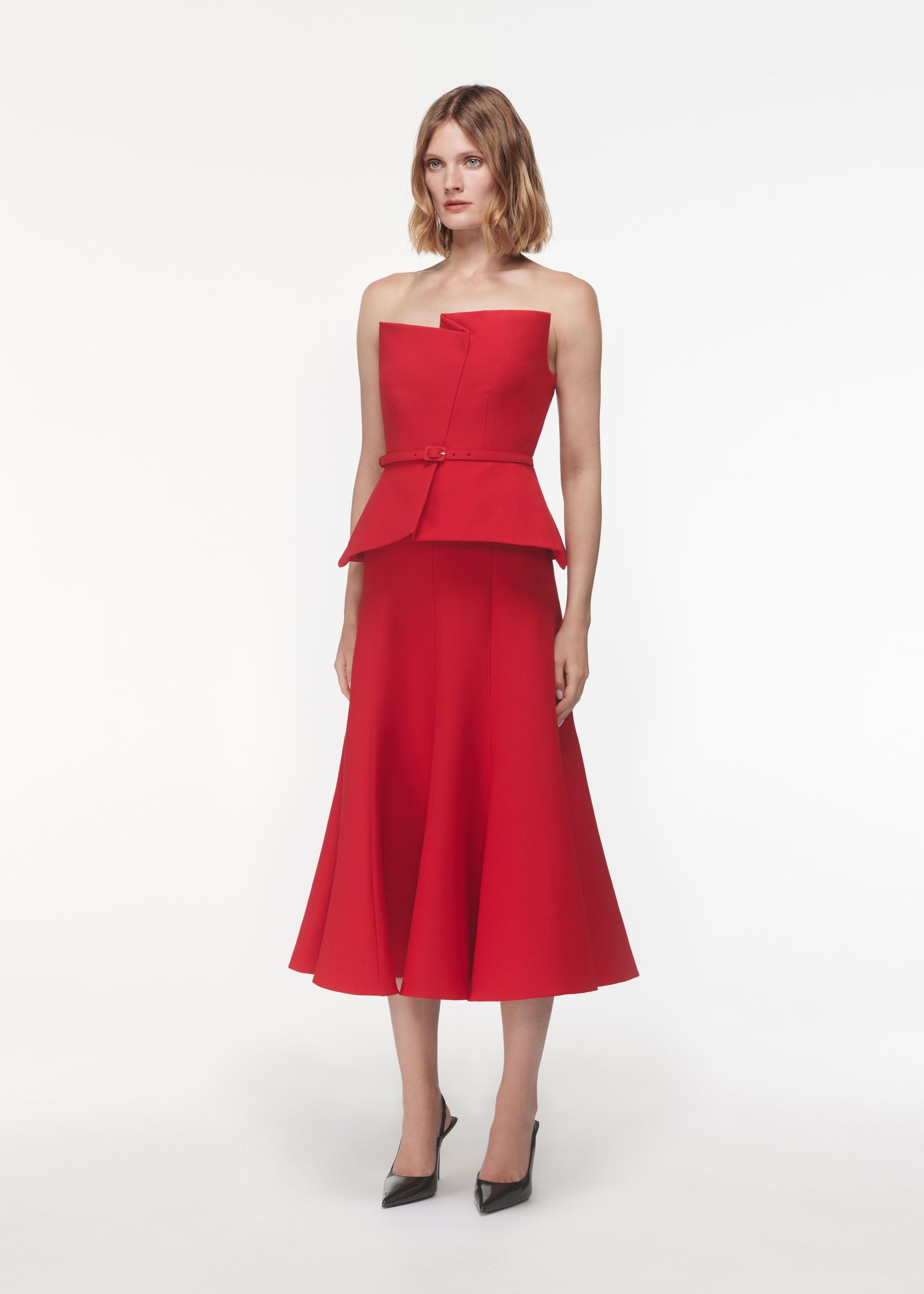 A photograph of a woman wearing a Strapless Wool Silk Peplum Midi Dress in Red