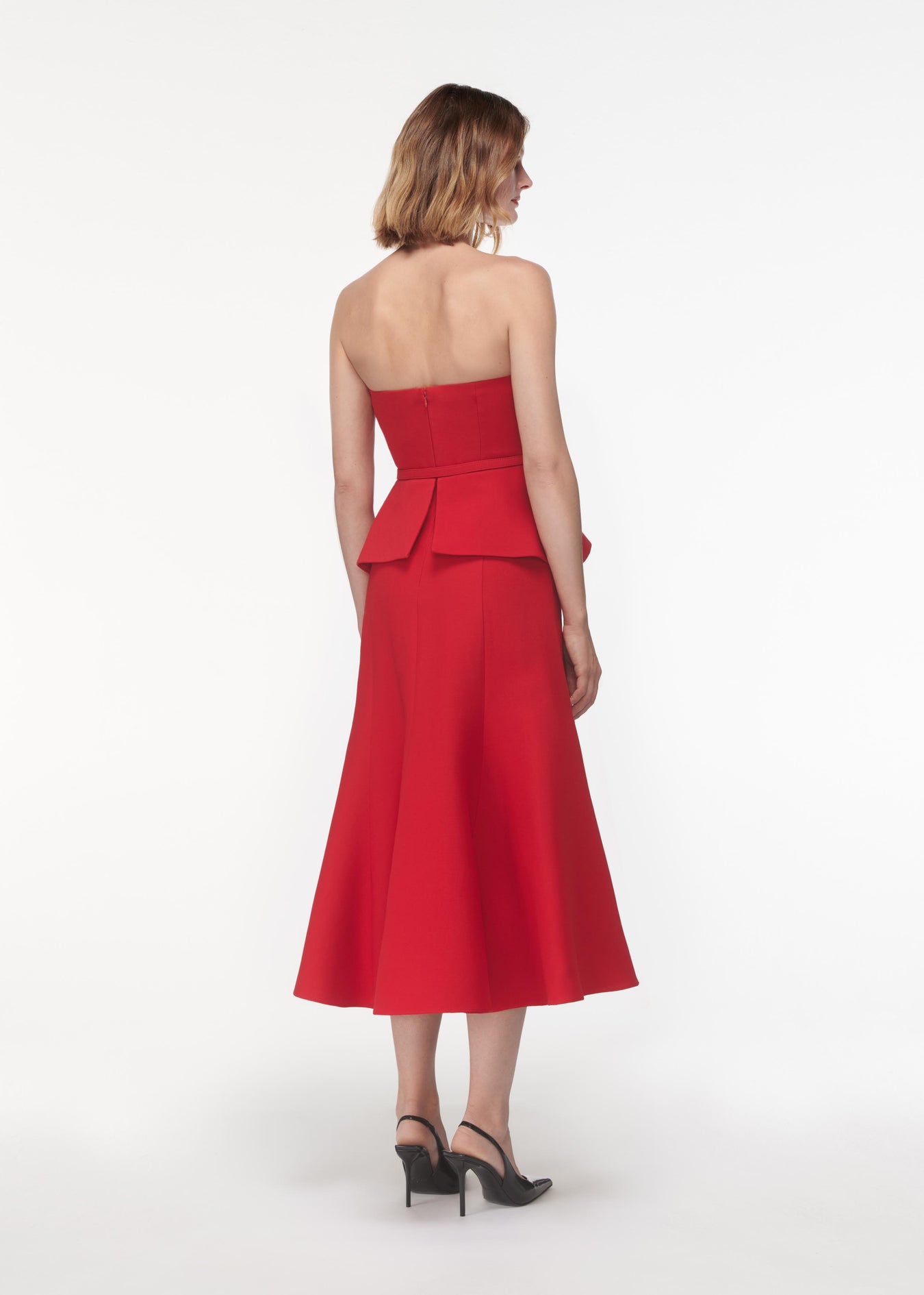 A photograph of a woman wearing a Strapless Wool Silk Peplum Midi Dress in Red