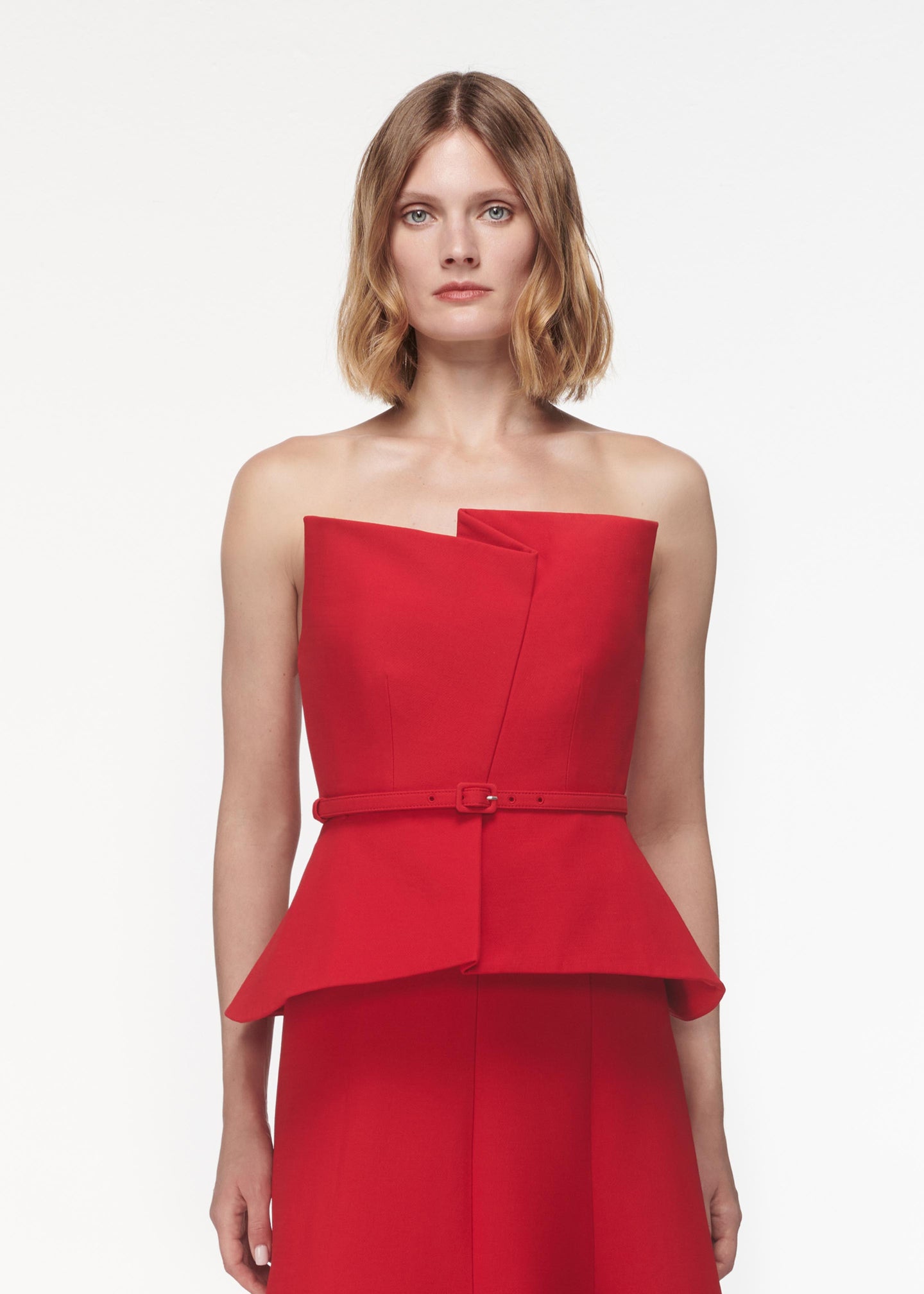 A photograph of a woman wearing a Strapless Wool Silk Peplum Midi Dress in Red