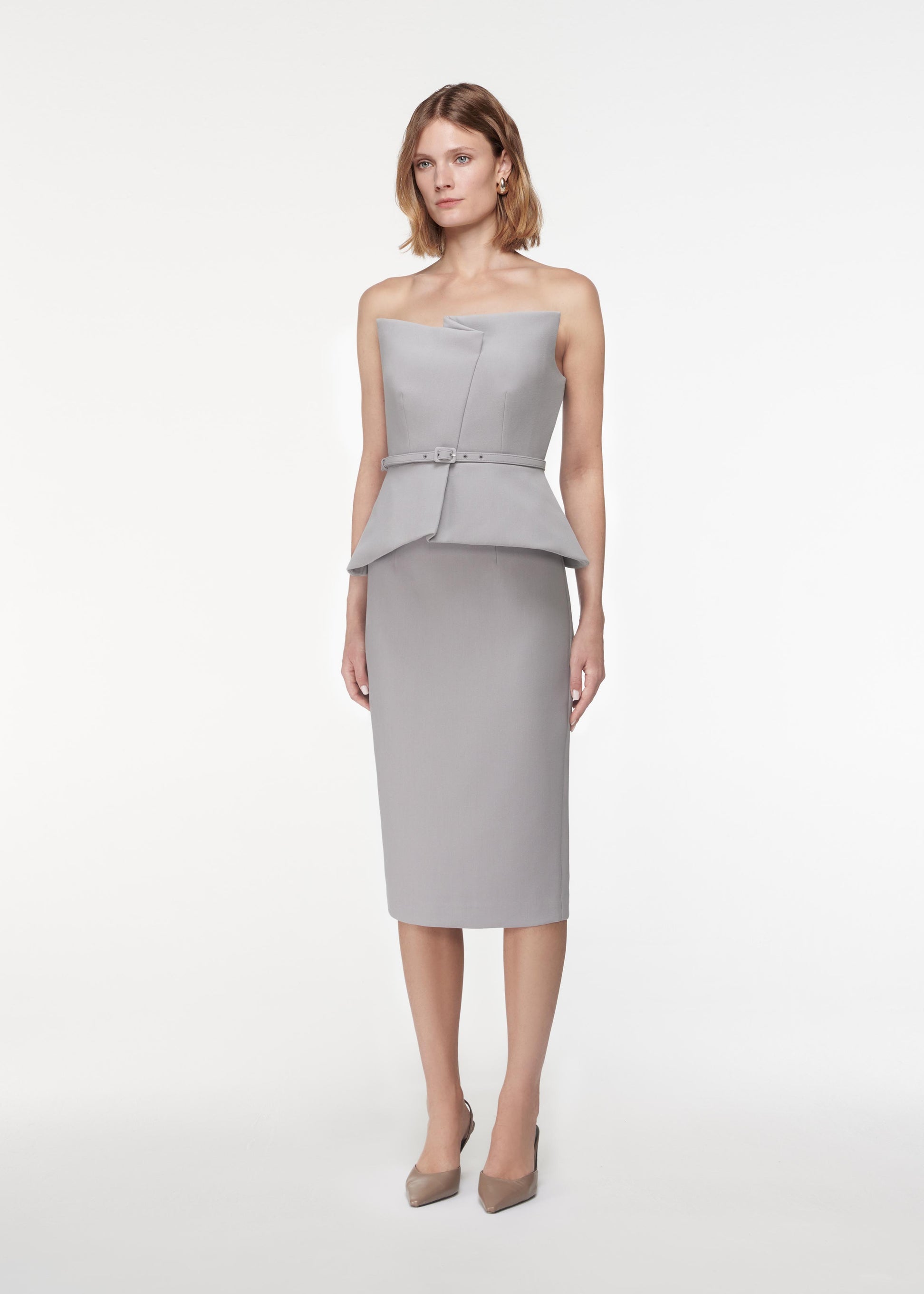 A photograph of a woman wearing a Strapless Crepe Peplum Top in Grey