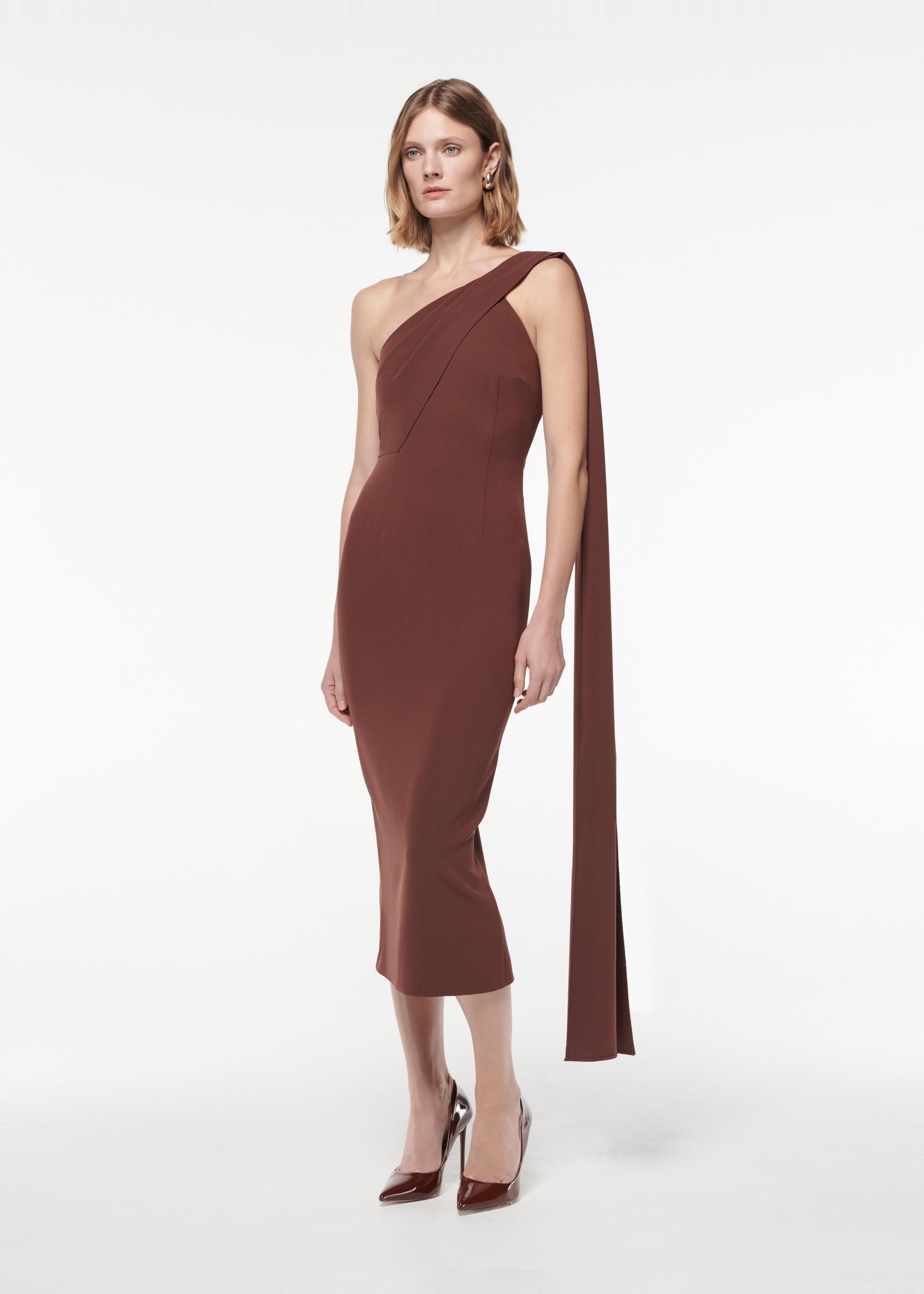 A photograph of a woman wearing a Asymmetric Heavy Cady Midi Dress in Brown