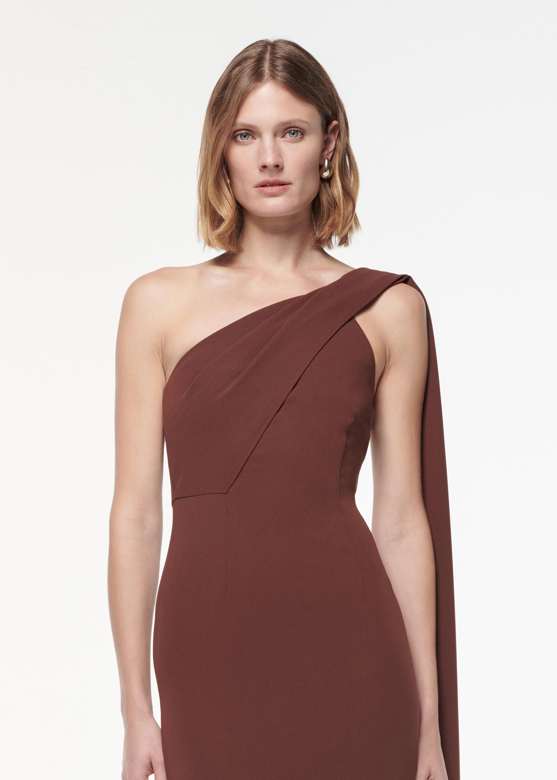A photograph of a woman wearing a Asymmetric Heavy Cady Midi Dress in Brown
