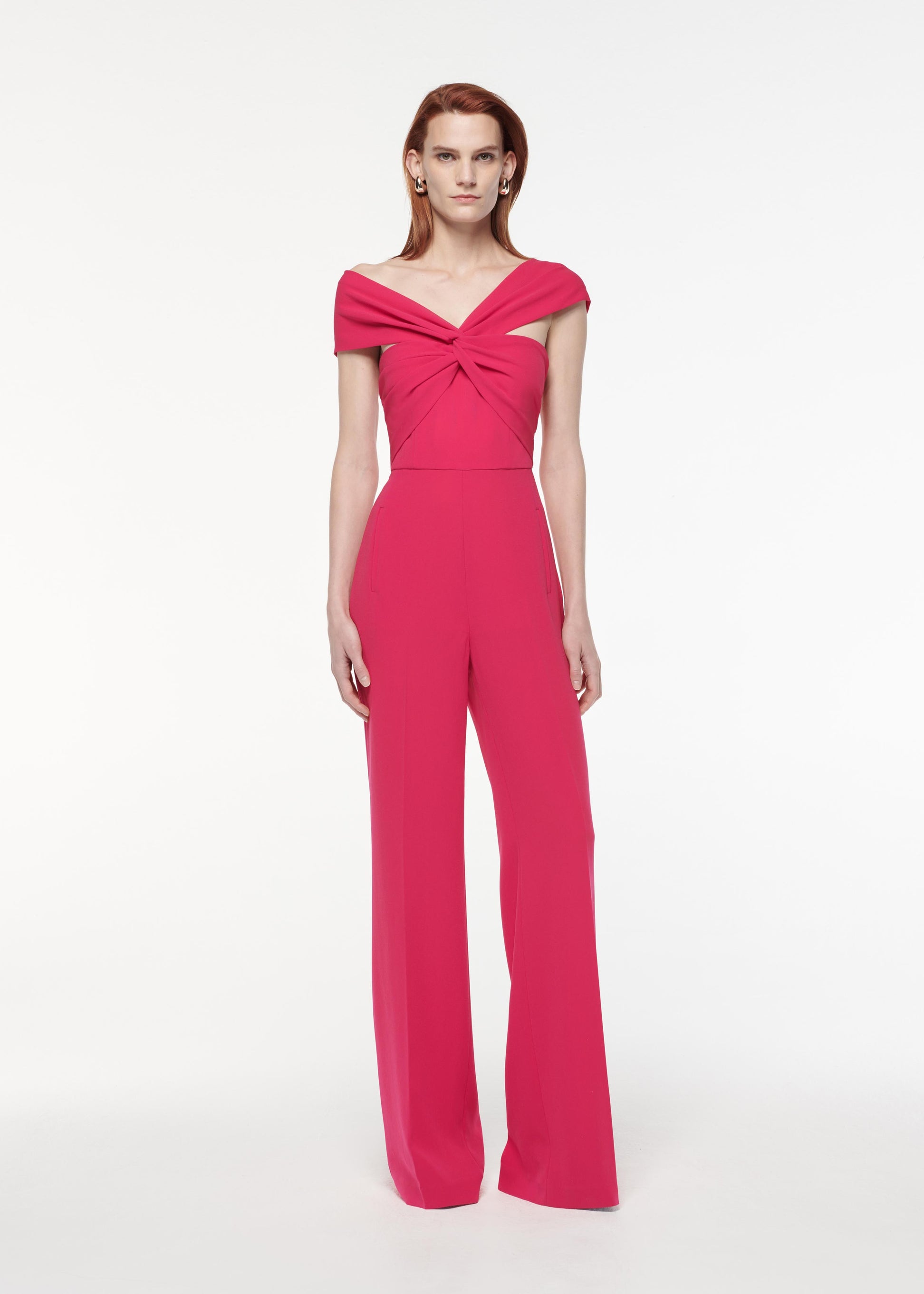 A photograph of a woman wearing a Asymmetric Light Cady Jumpsuit in Pink