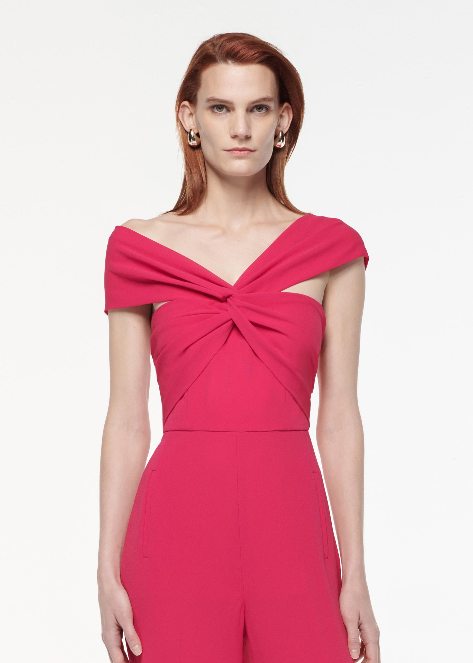 A photograph of a woman wearing a Asymmetric Light Cady Jumpsuit in Pink