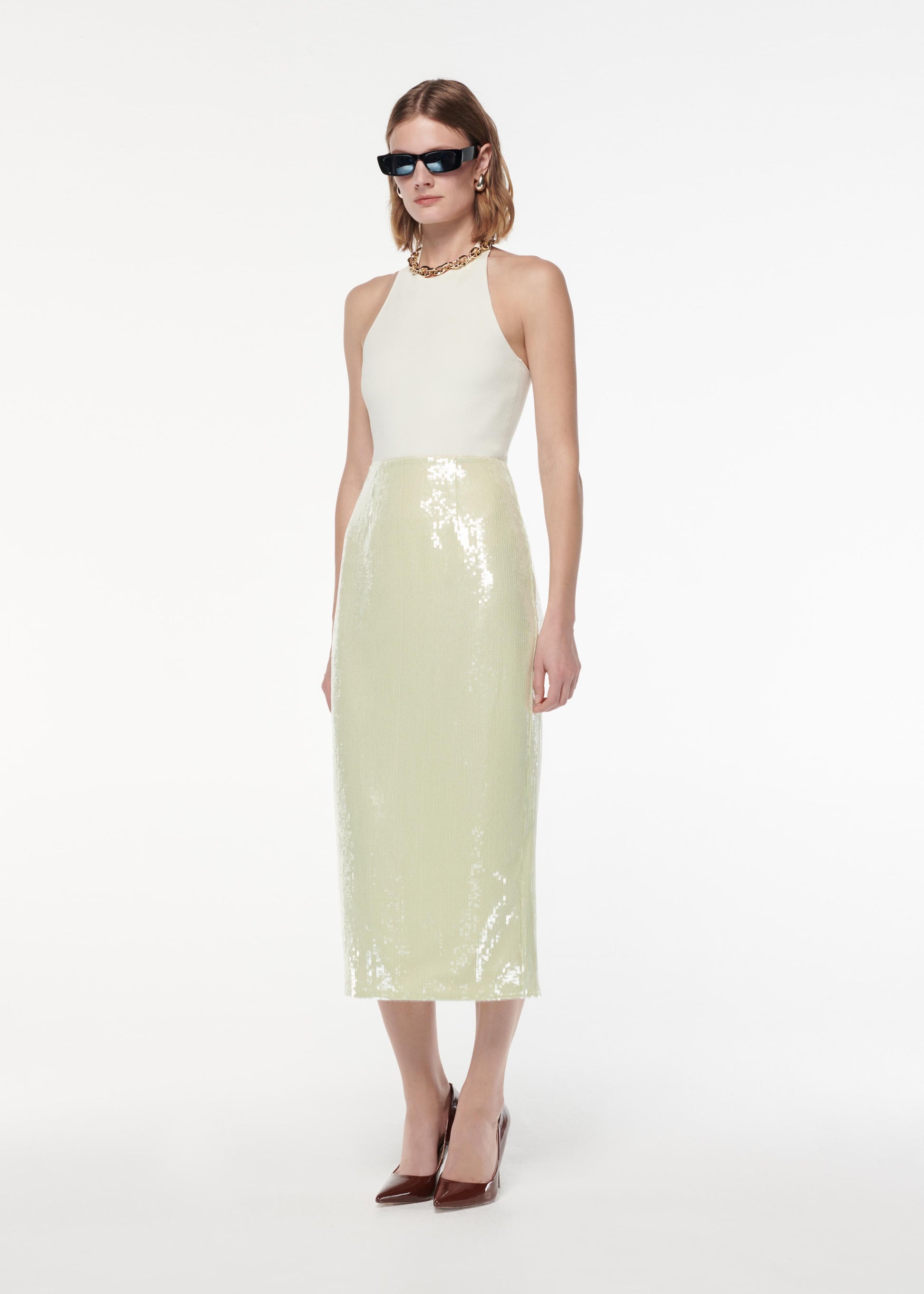 A photograph of a woman wearing a Sequin Midi Skirt in Green