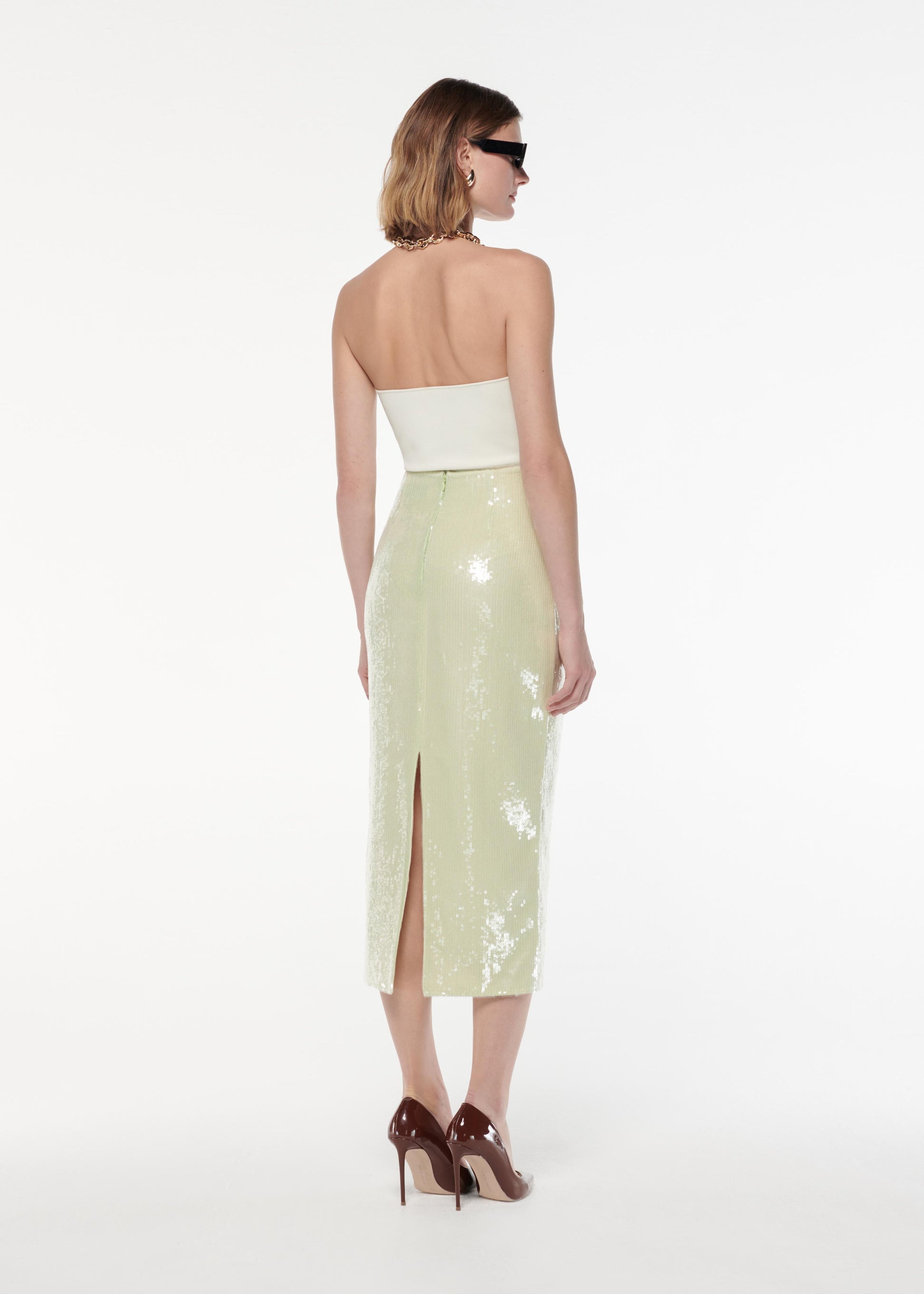 A photograph of a woman wearing a Sequin Midi Skirt in Green