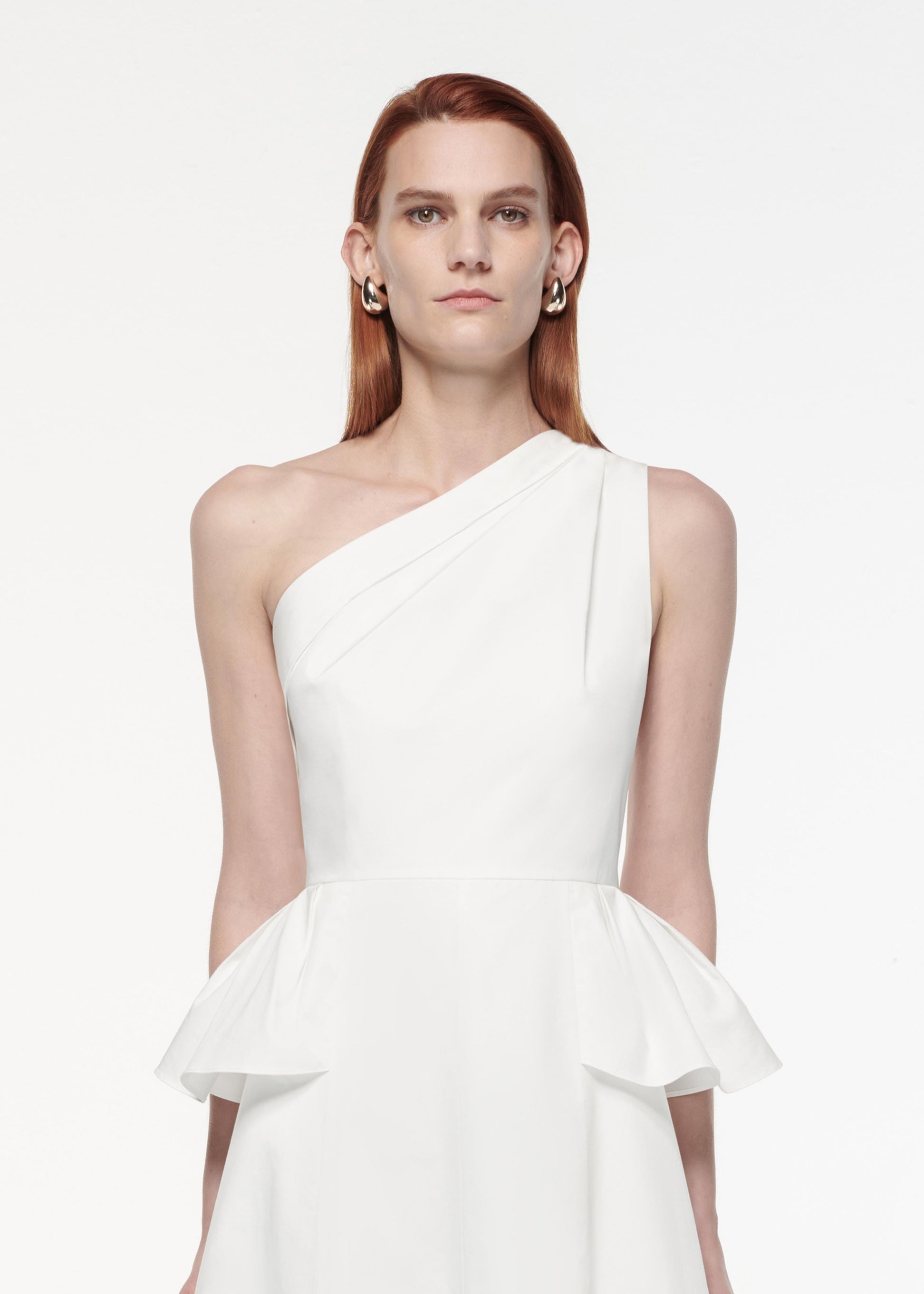 A photograph of a woman wearing a Asymmetric Hip Detail Dress in White