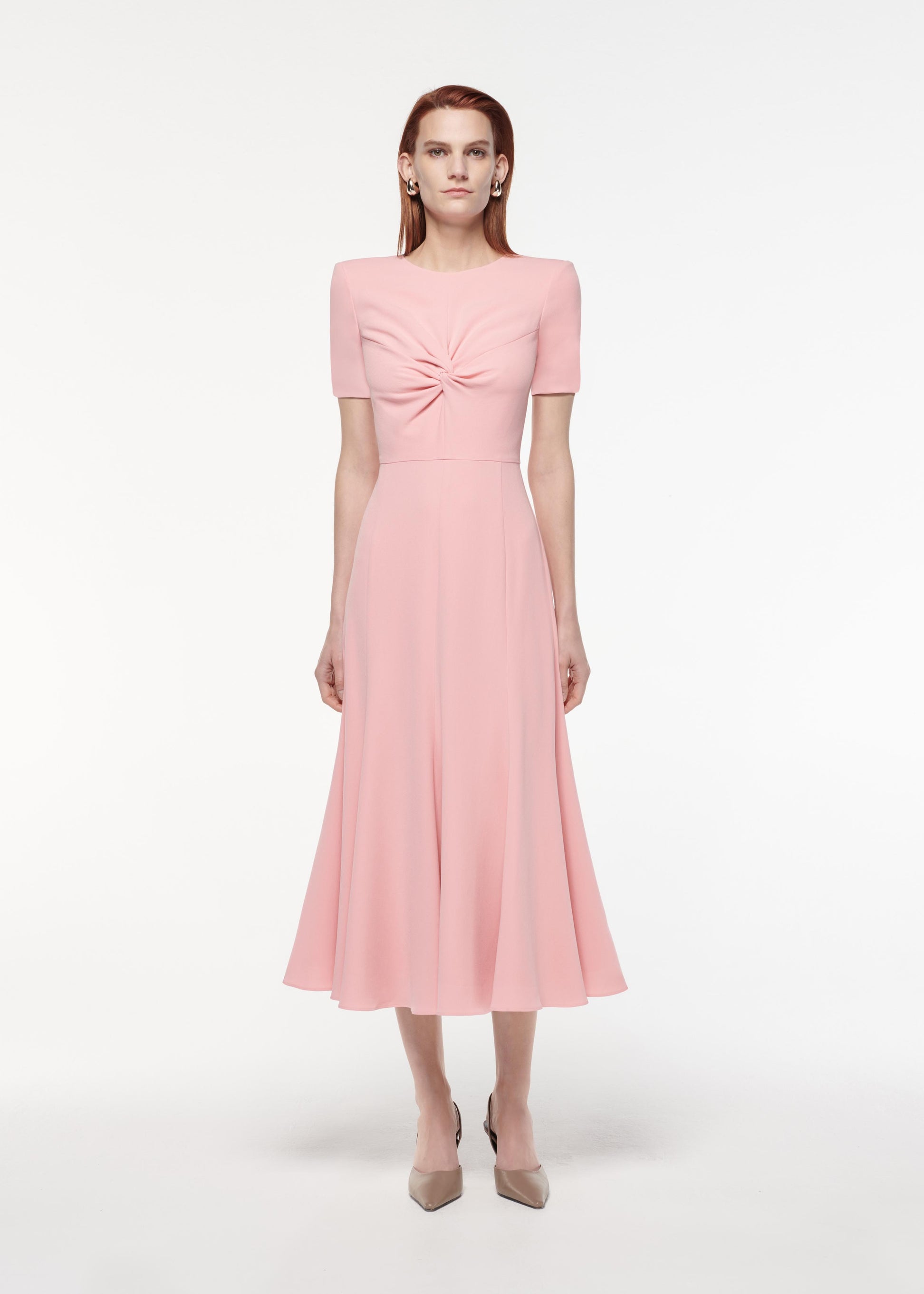 A photograph of a woman wearing a Short Sleeve Light Cady Midi Dress in Pink