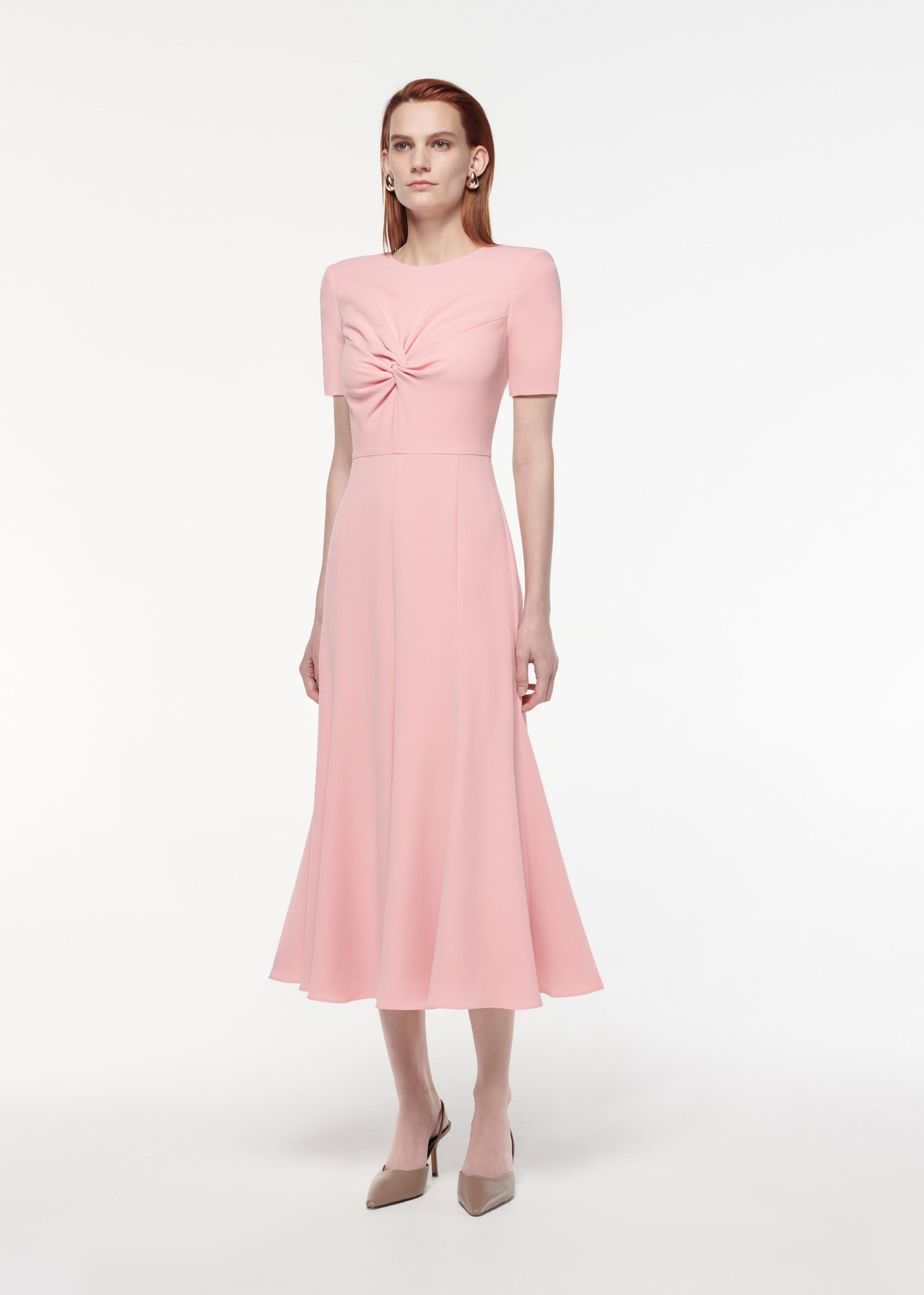 A photograph of a woman wearing a Short Sleeve Light Cady Midi Dress in Pink