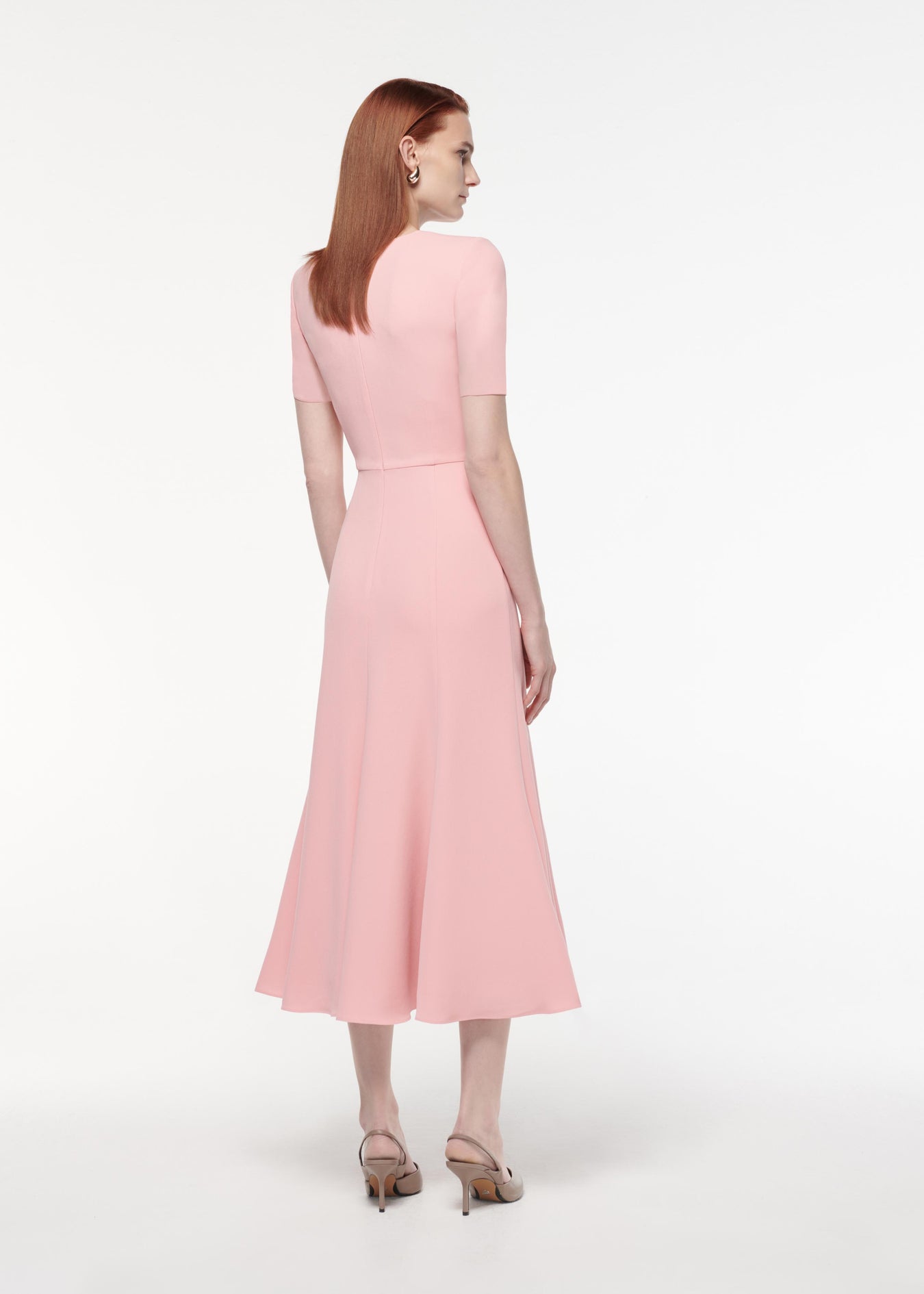 A photograph of a woman wearing a Short Sleeve Light Cady Midi Dress in Pink