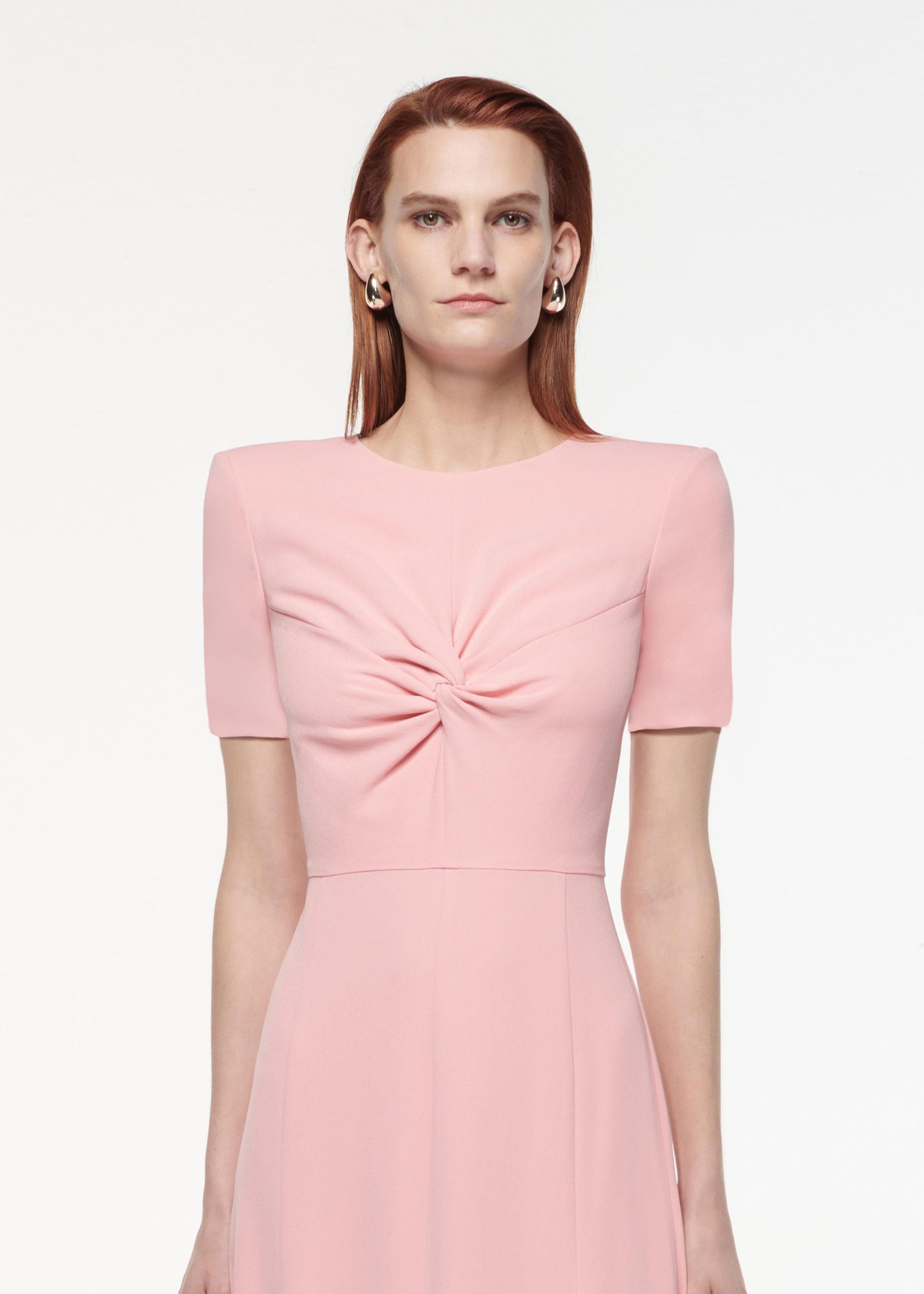 A photograph of a woman wearing a Short Sleeve Light Cady Midi Dress in Pink