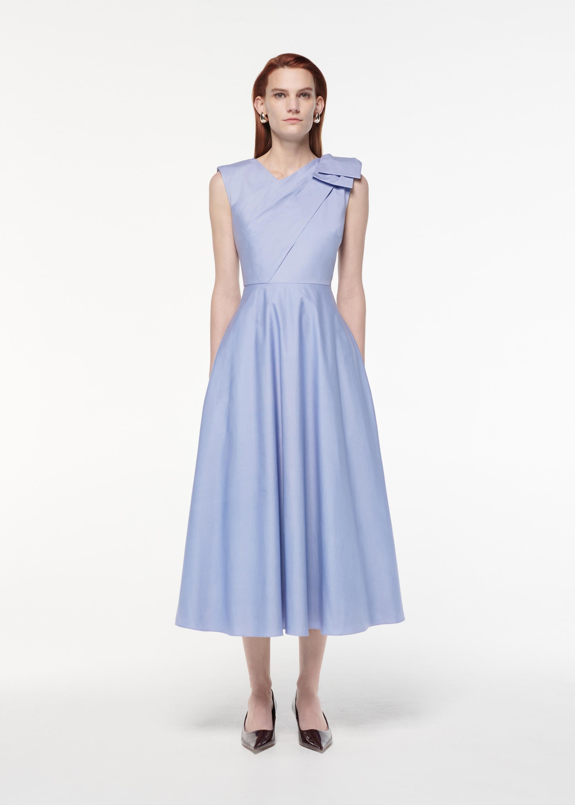A photograph of a woman wearing a Bow Cotton Poplin Midi Dress in Blue