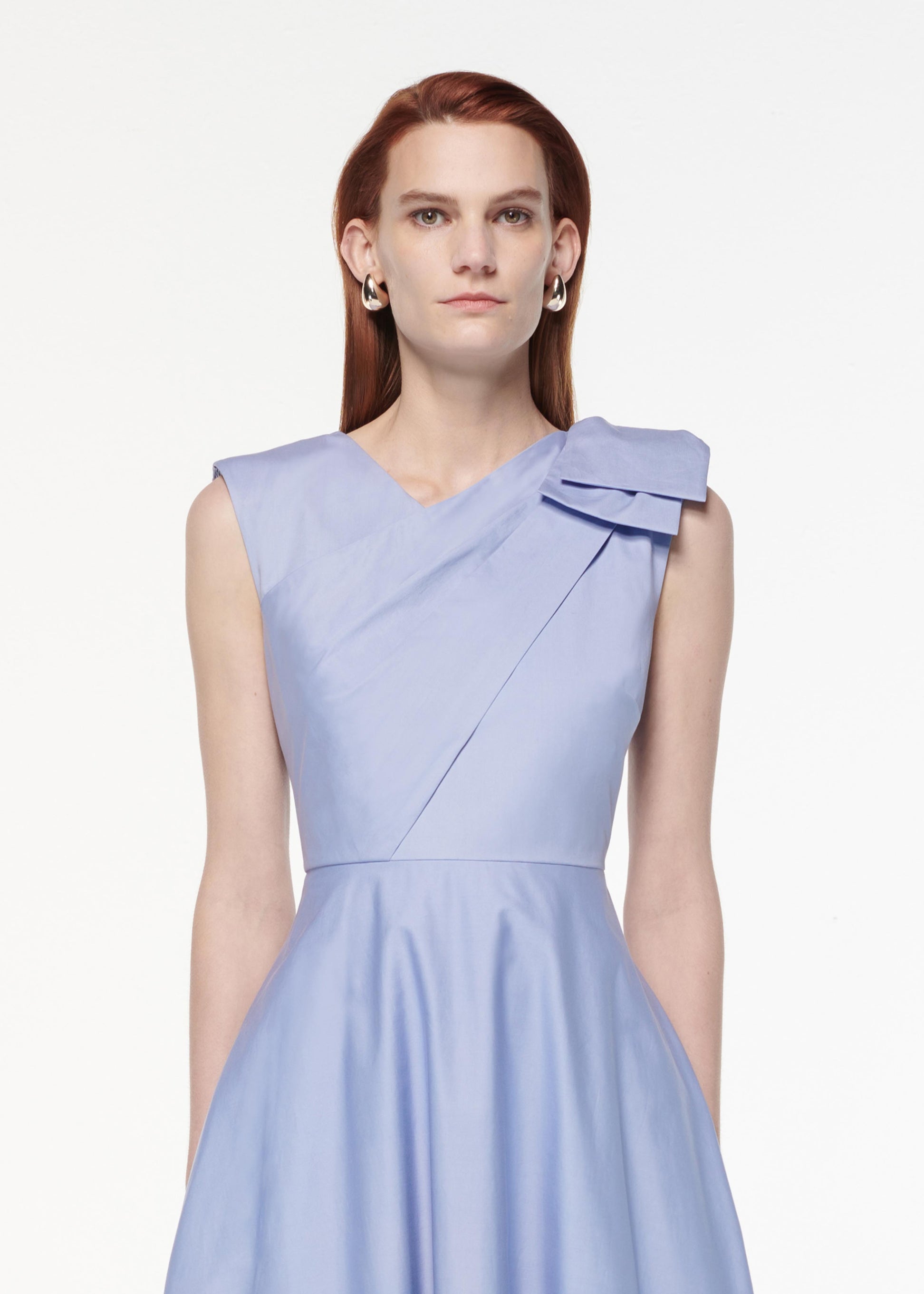 A photograph of a woman wearing a Bow Cotton Poplin Midi Dress in Blue