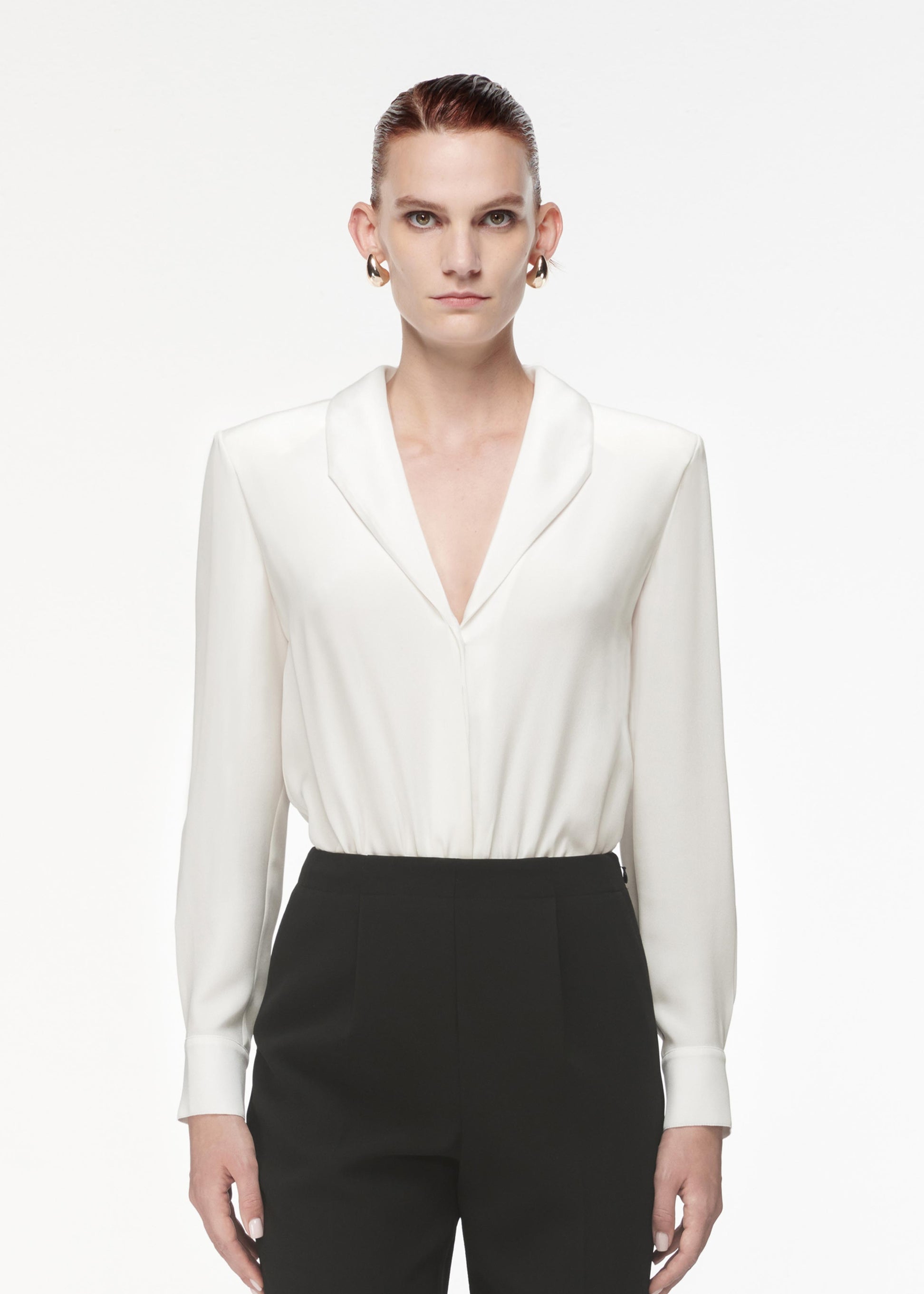 A photograph of a woman wearing a Silk Shirt Bodysuit in White