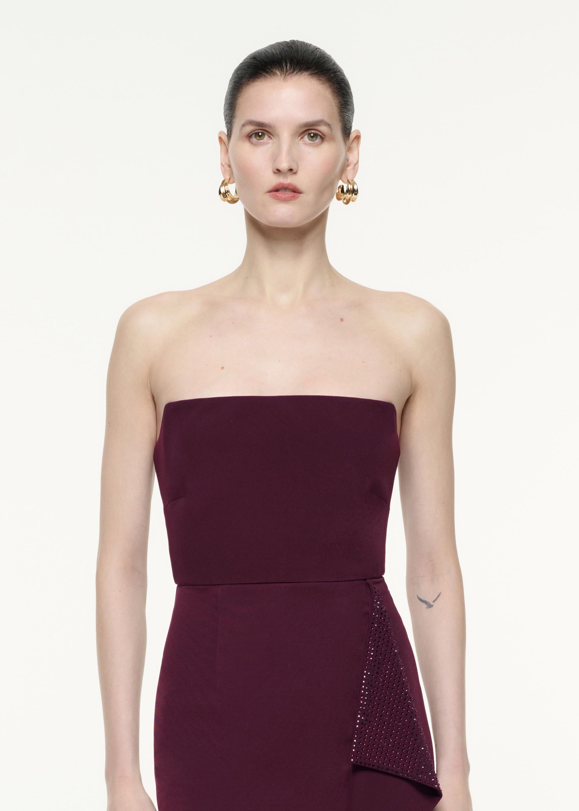 A close up image of a model wearing the Strapless Diamante Ruffle Midi Dress in Aubergine