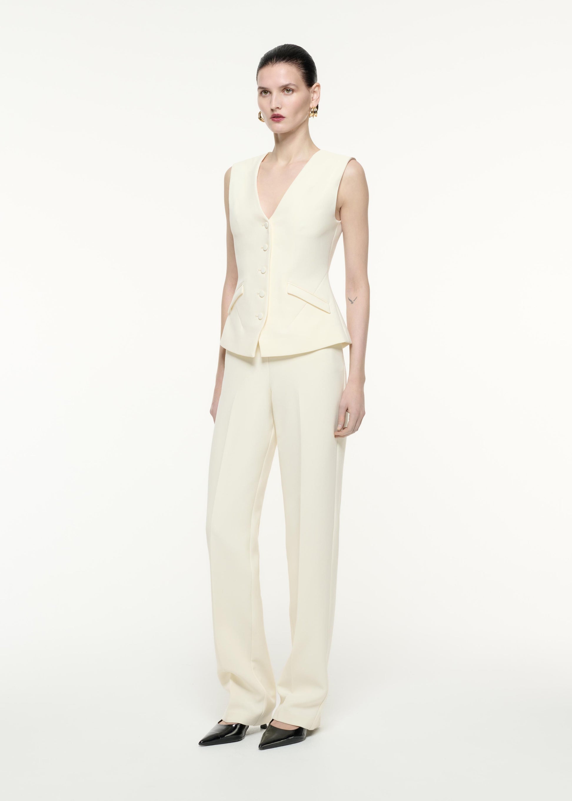 A side view image of a model wearing the Crepe Trouser in Cream