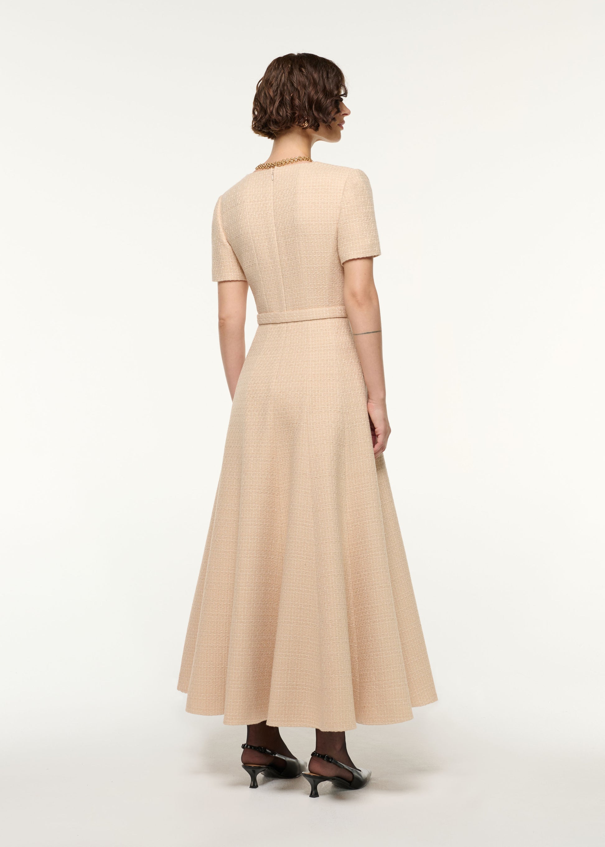 Back view of a model wearing the Folded Collar Belted Boucle Dress in Dark Cream