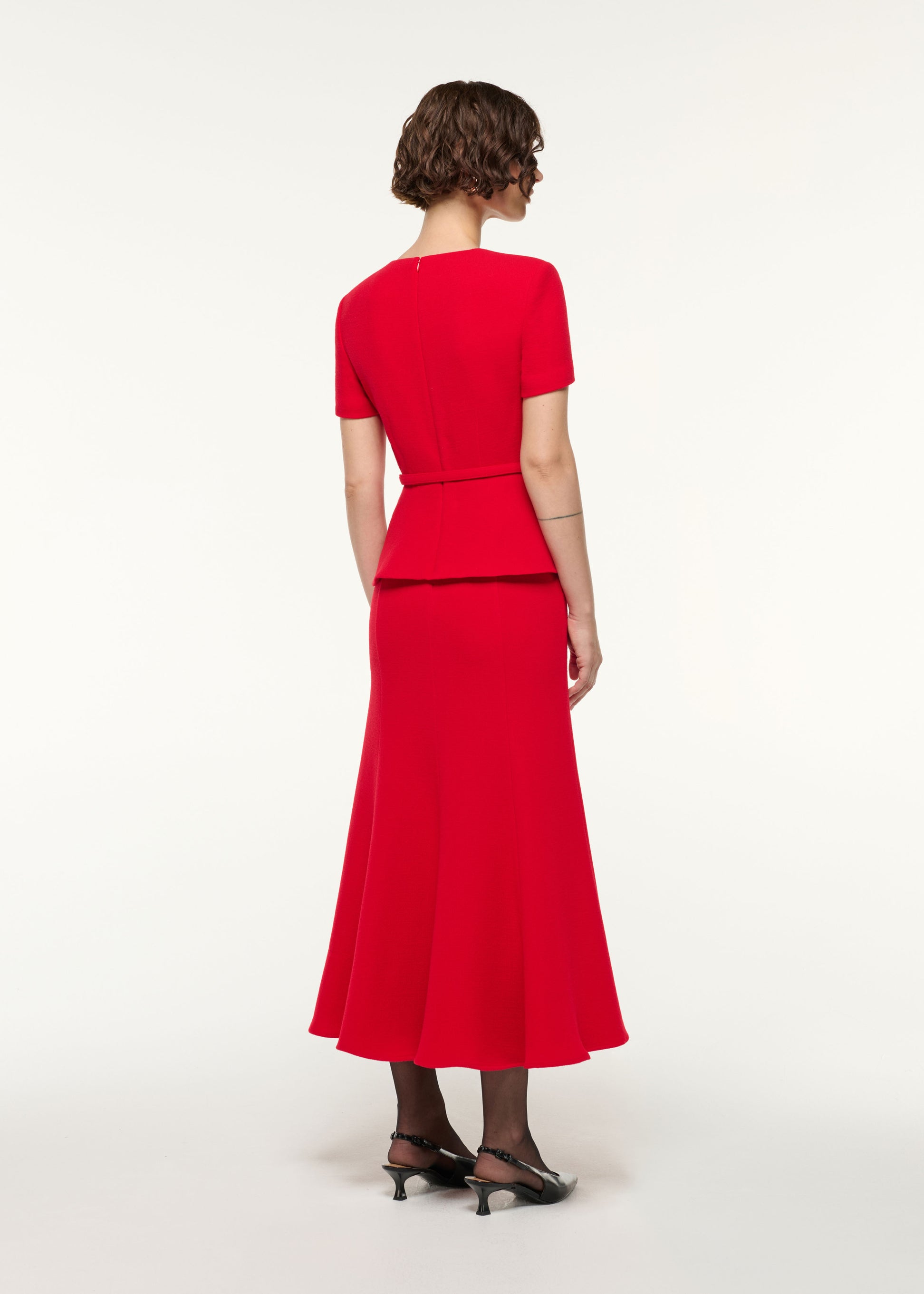 Back view of a model wearing the Wool Origami Peplum Drape Dress in Red