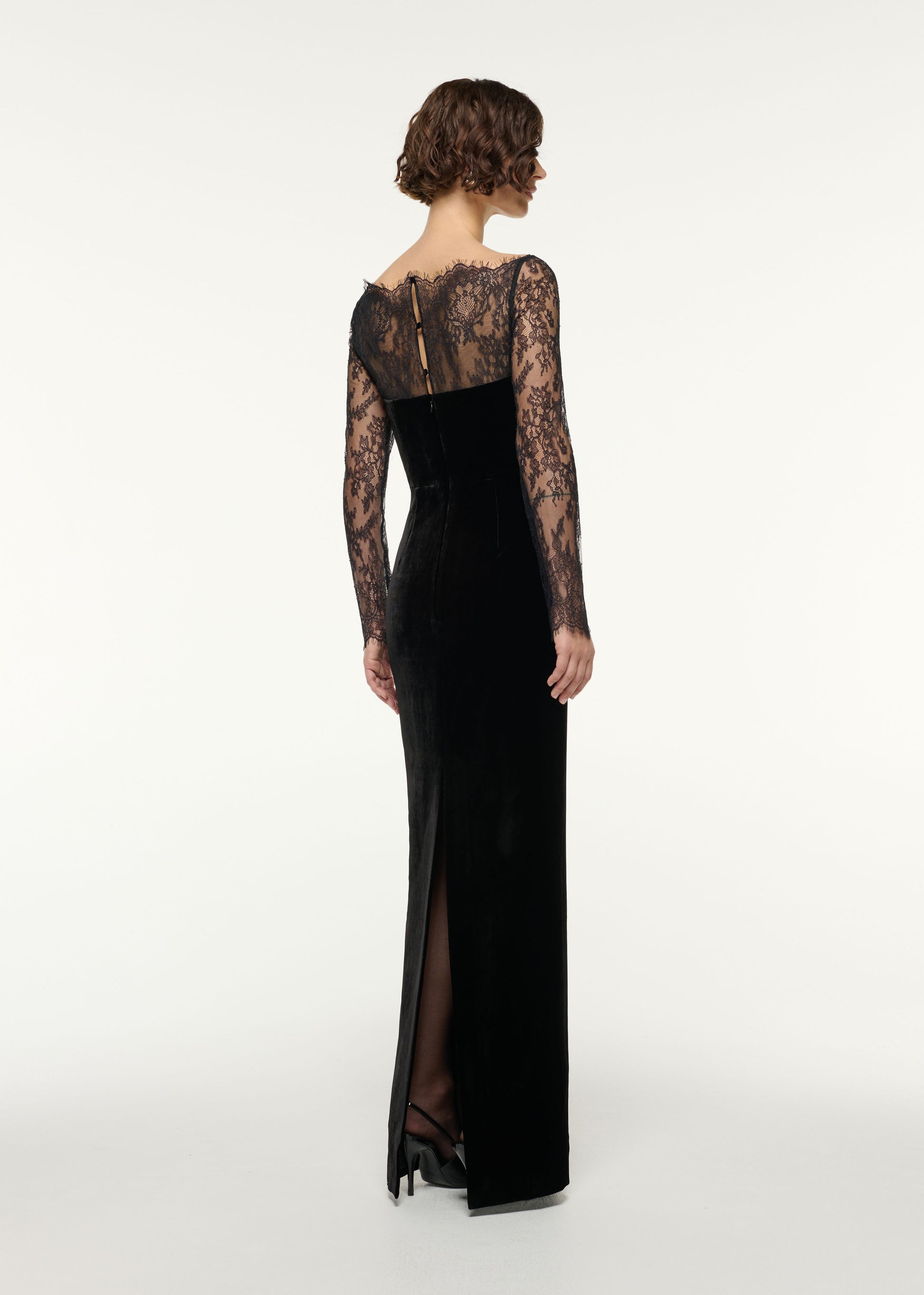 Back view of a model wearing the Scalloped Lace And Velvet Gown in Black