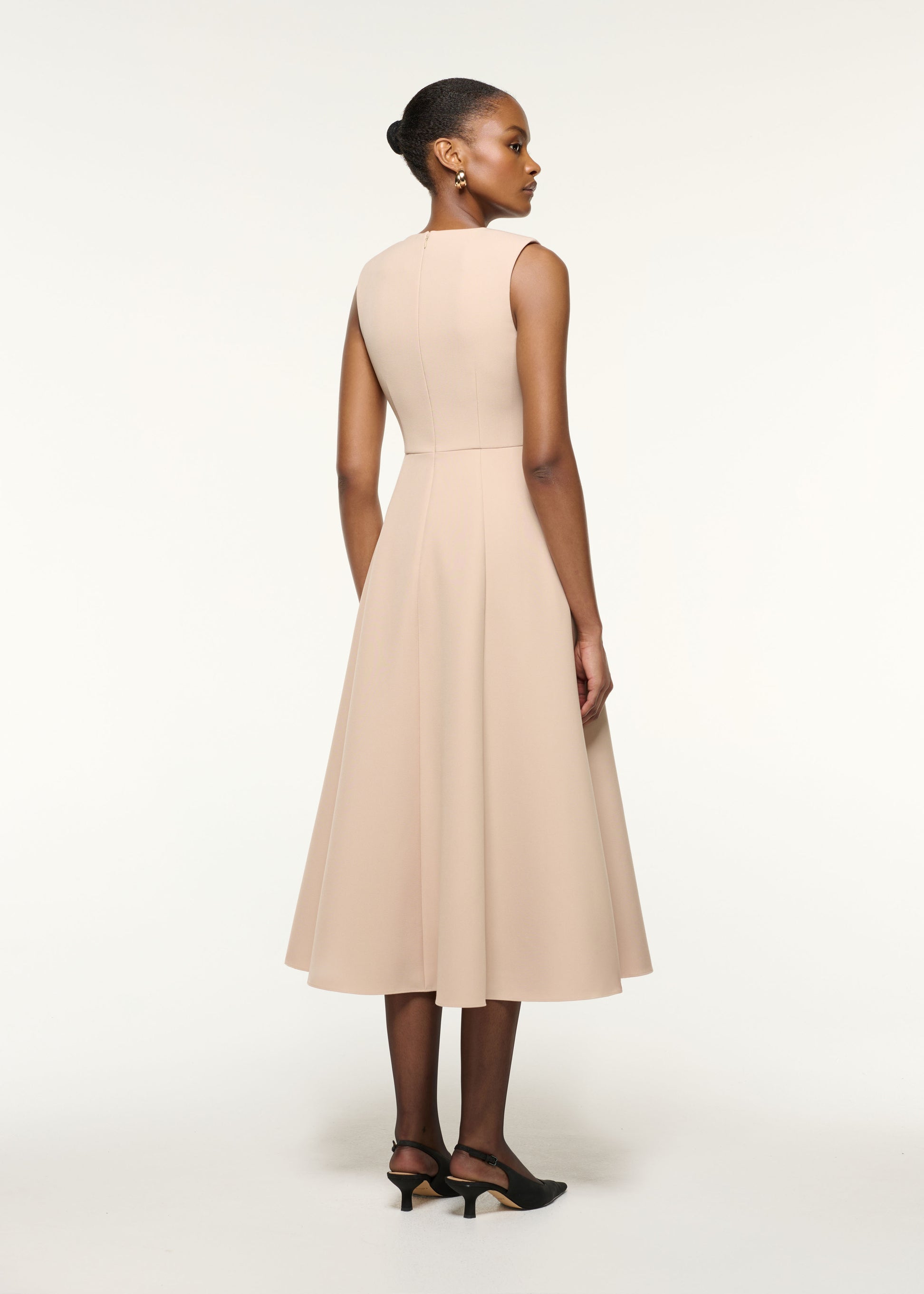 Back view of a model wearing the Origami Bust Line Flared Midi Dress in Cream