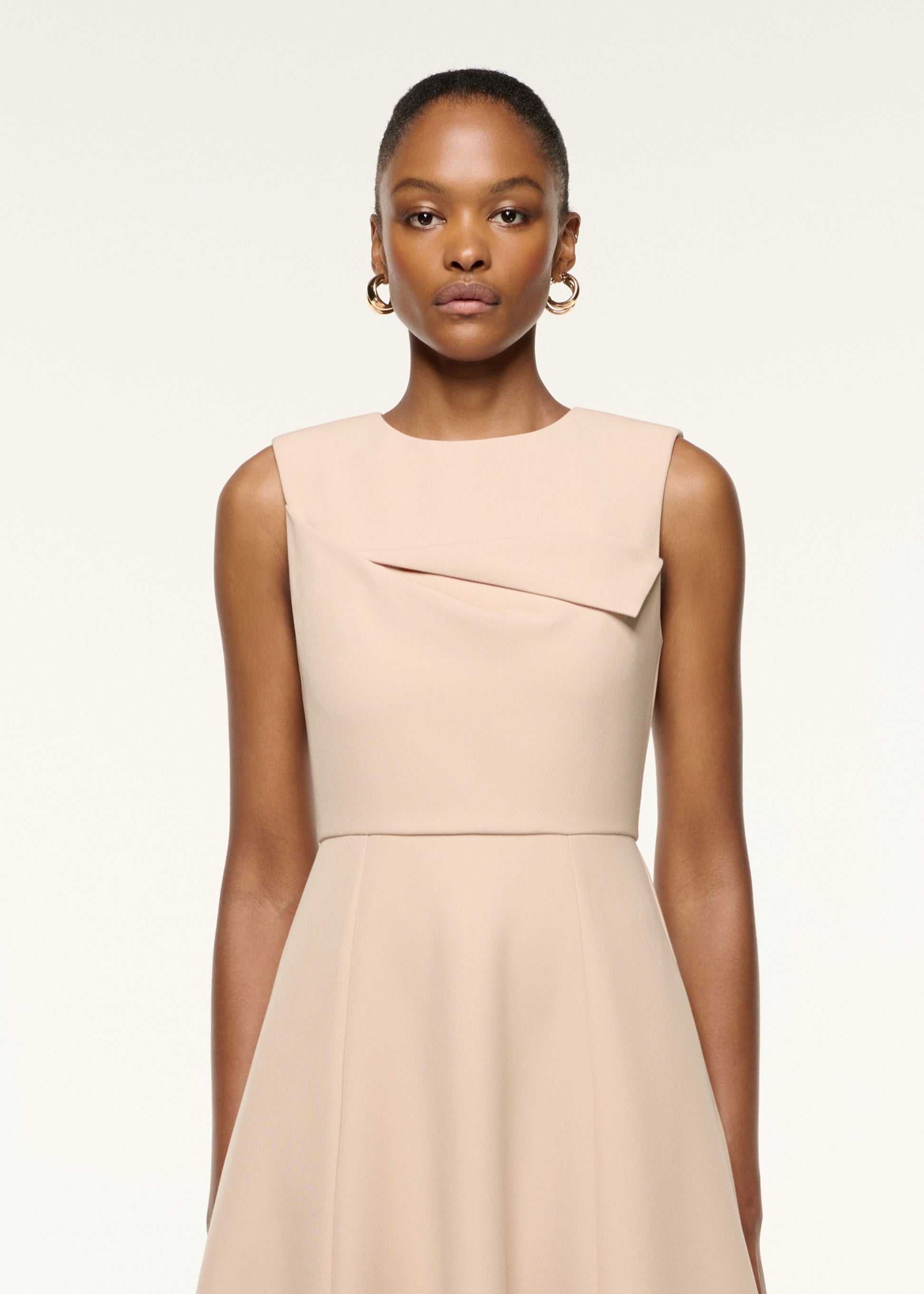 Close up of a model wearing the Origami Bust Line Flared Midi Dress in Cream