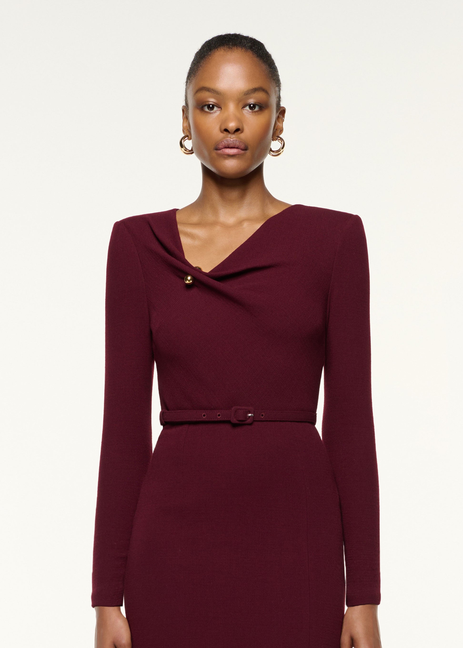 Close up of a model wearing the Asymmetrical Draped Neck Belted Wool Dress in Mulberry
