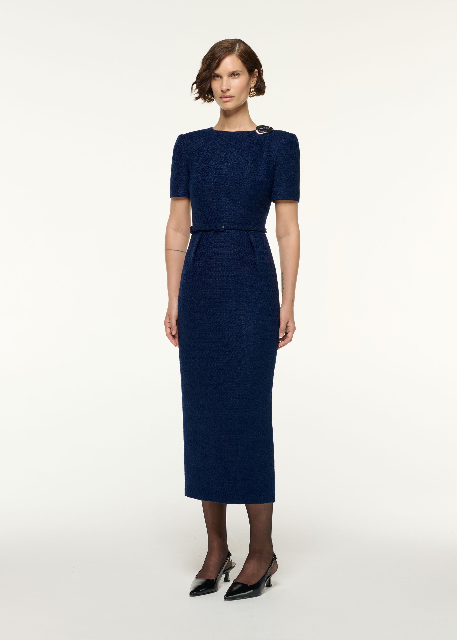 Side view of a model wearing the Twisted Silver Brooch Belted Boucle Dress in Navy