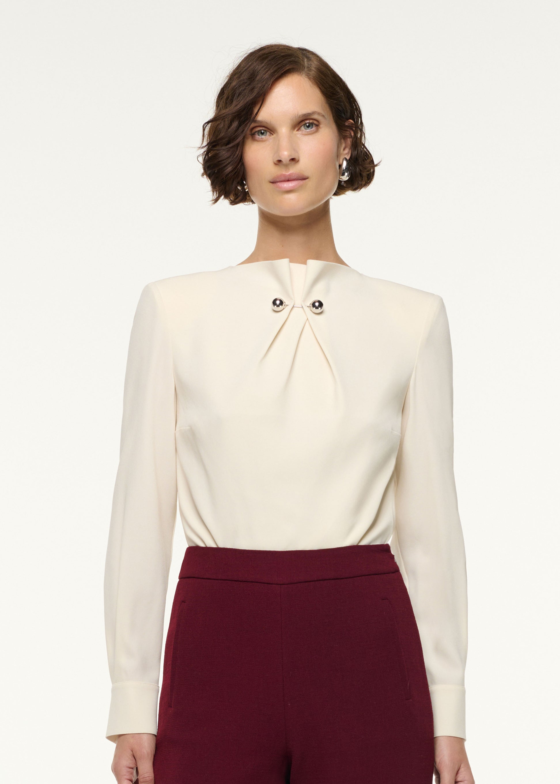 Close up of a model wearing the Gathered Silver Brooch Blouson Bodysuit in Cream