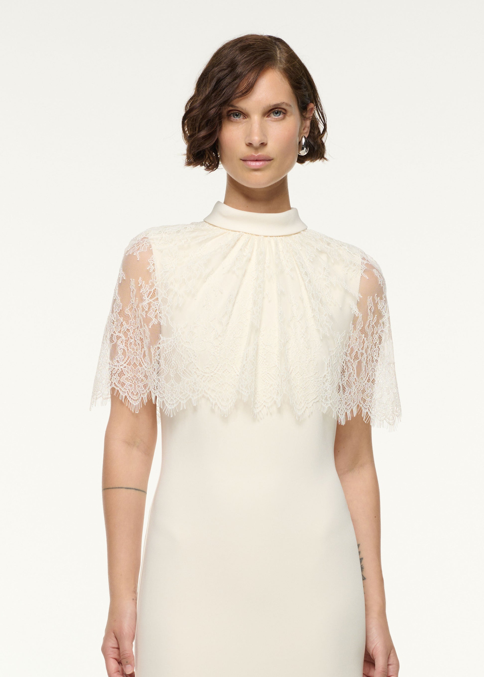 Close up of a model wearing the Scallop Lace Shawl Column Midi Dress in Cream