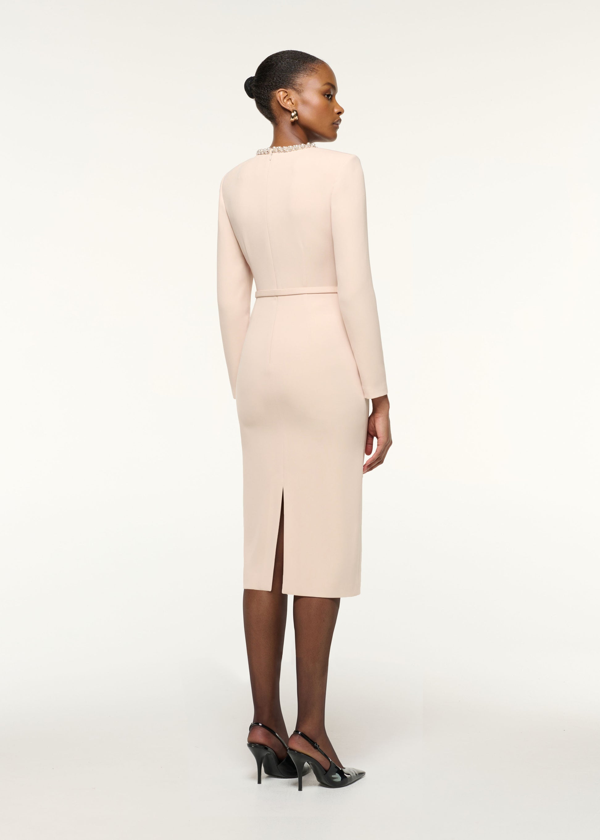 Back view of a model wearing the Twisted Drape Pearl Trim Neckline Dress in Cream