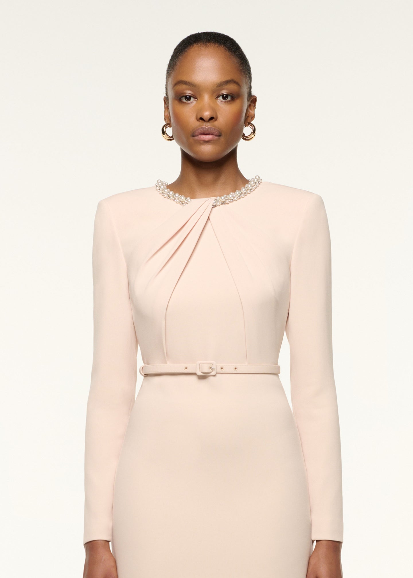 Close up of a model wearing the Twisted Drape Pearl Trim Neckline Dress in Cream