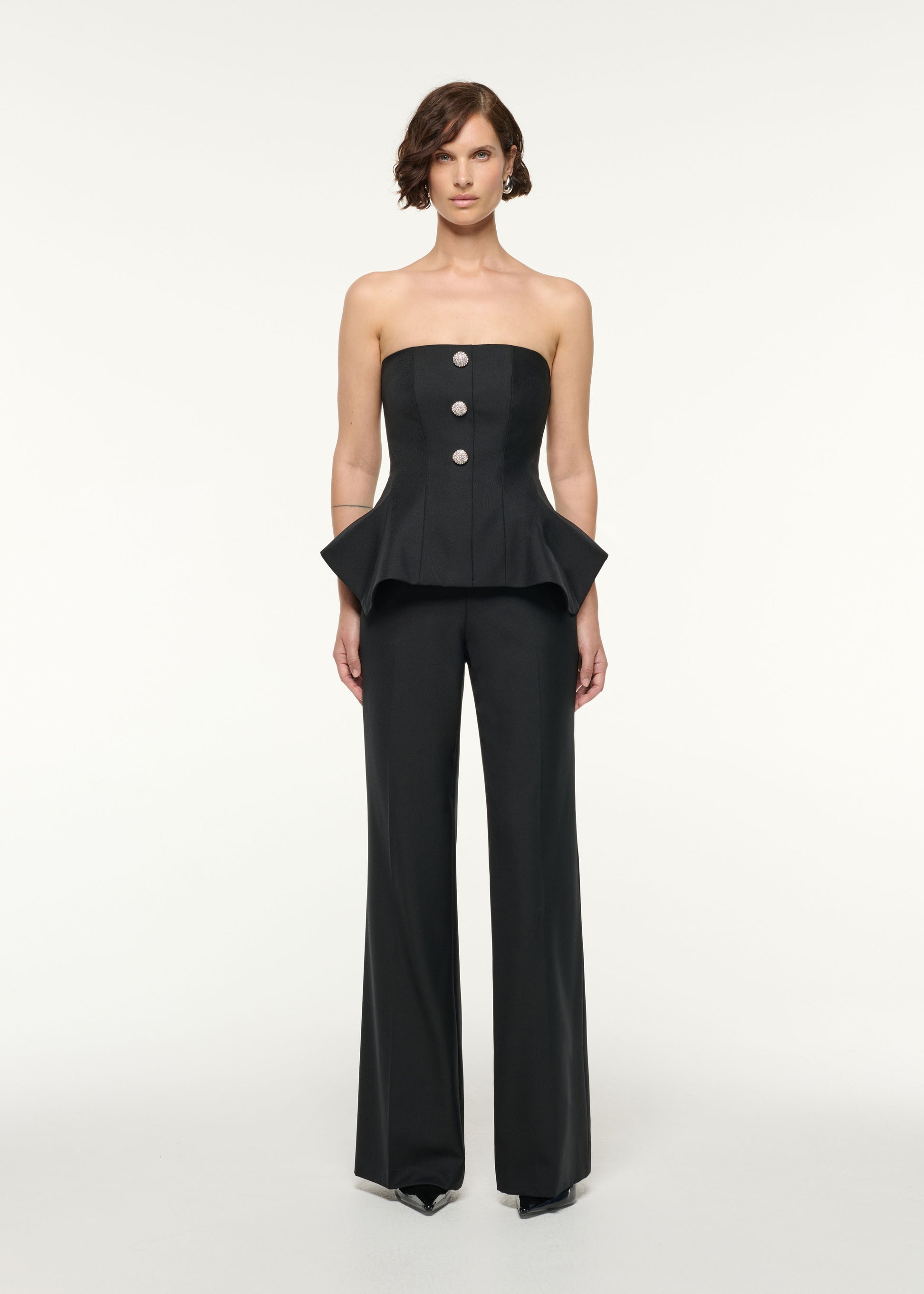 Front view of a model wearing the Crystal Button Peplum Wool Jumpsuit in Black
