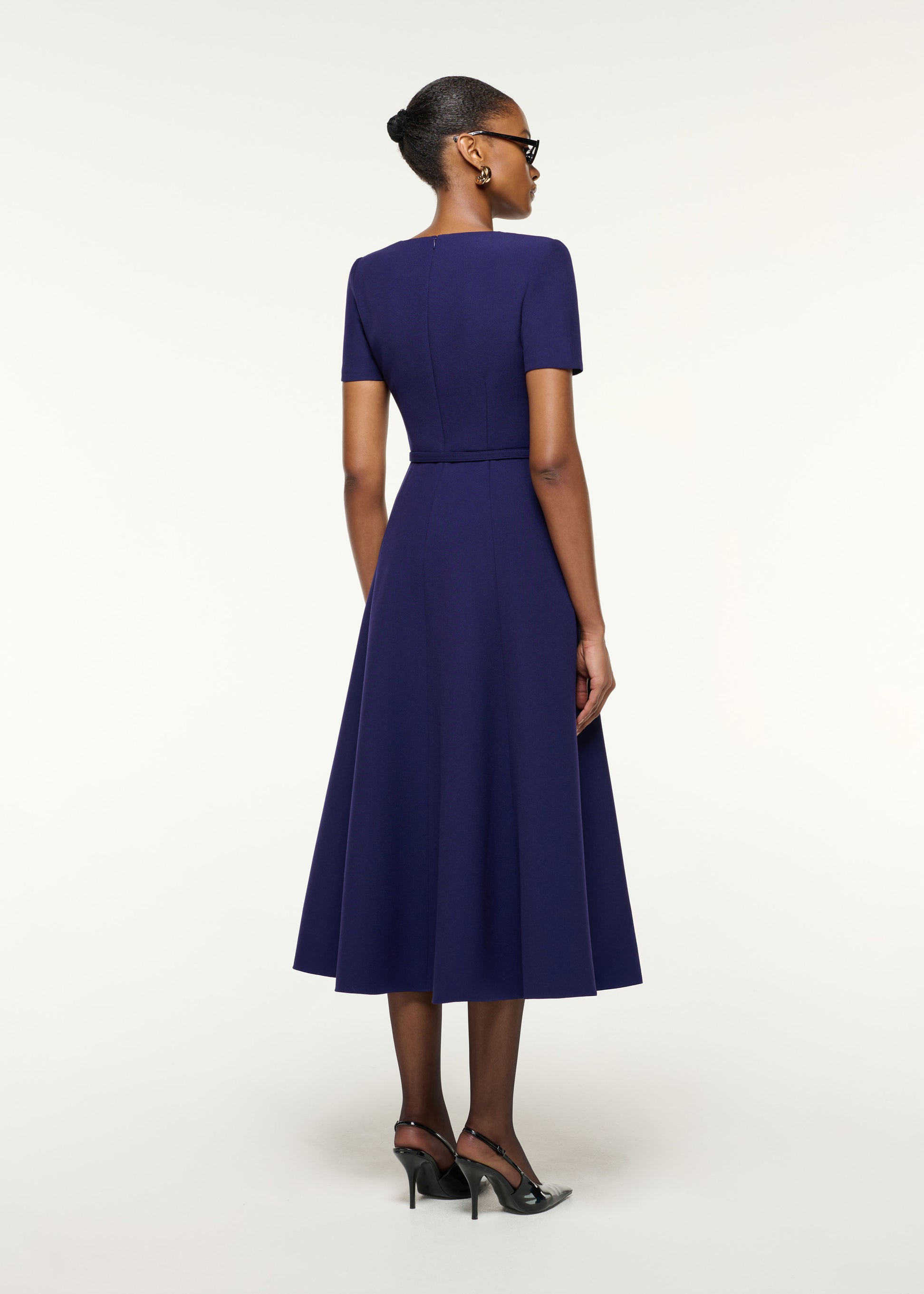 Back view of a model wearing the Asymmetrical Neckline Crepe Midi Dress in Navy