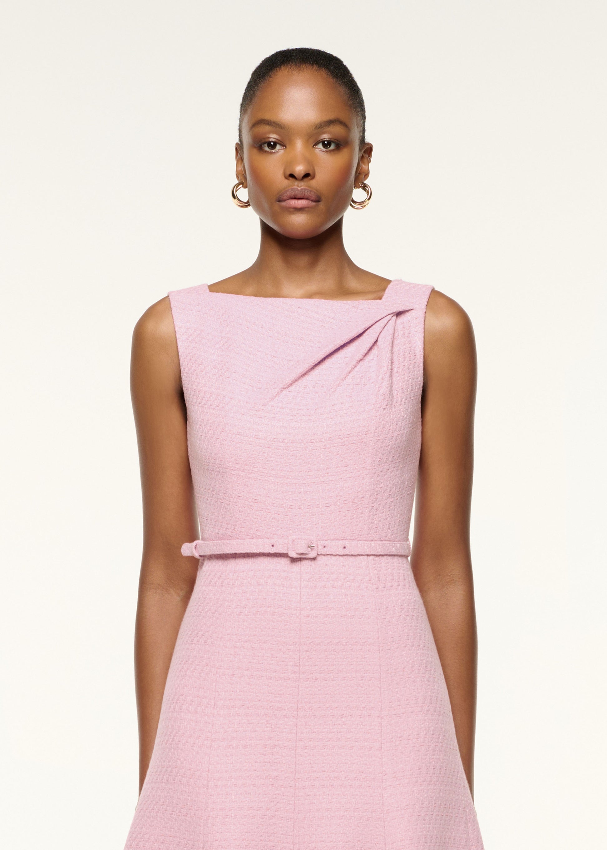Close up of a model wearing the Asymmetrical Twist Belted Boucle Dress in Pink