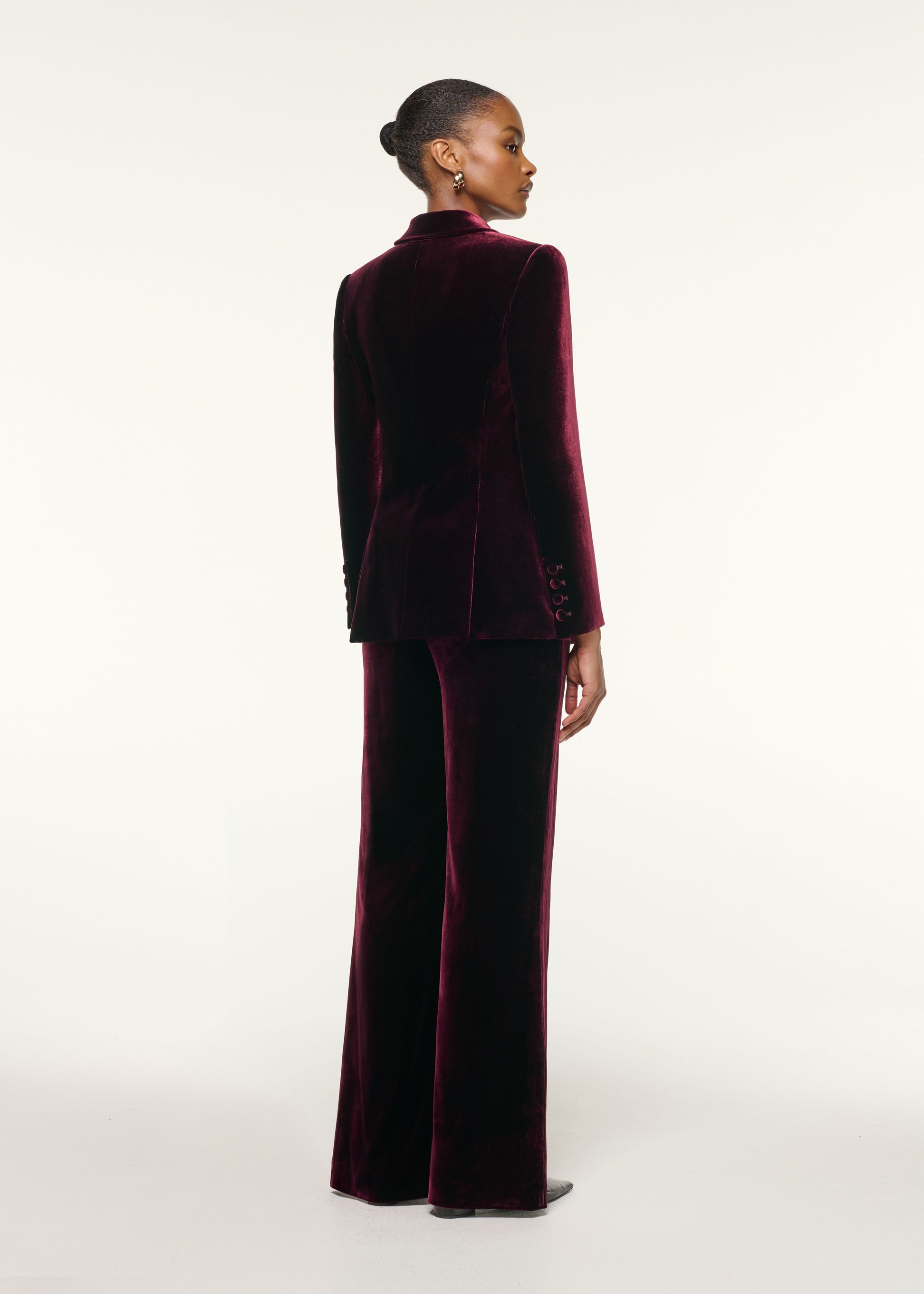 Back view of a model wearing the Tailored Velvet Wide Leg Trouser in Mulberry