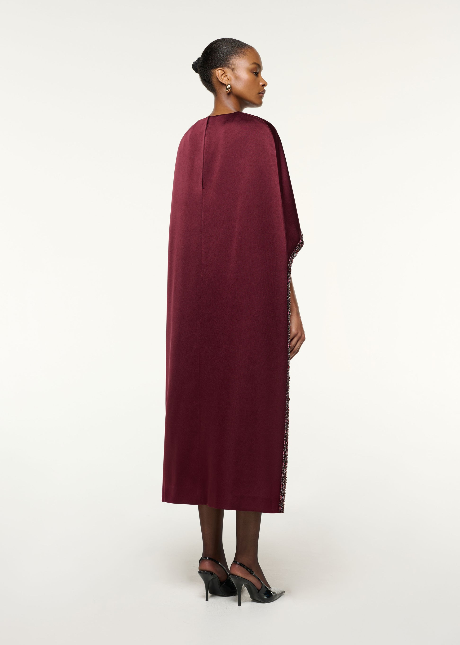 Back view of a model wearing the Crystal Trimmed Cape Midi Dress in Mulberry
