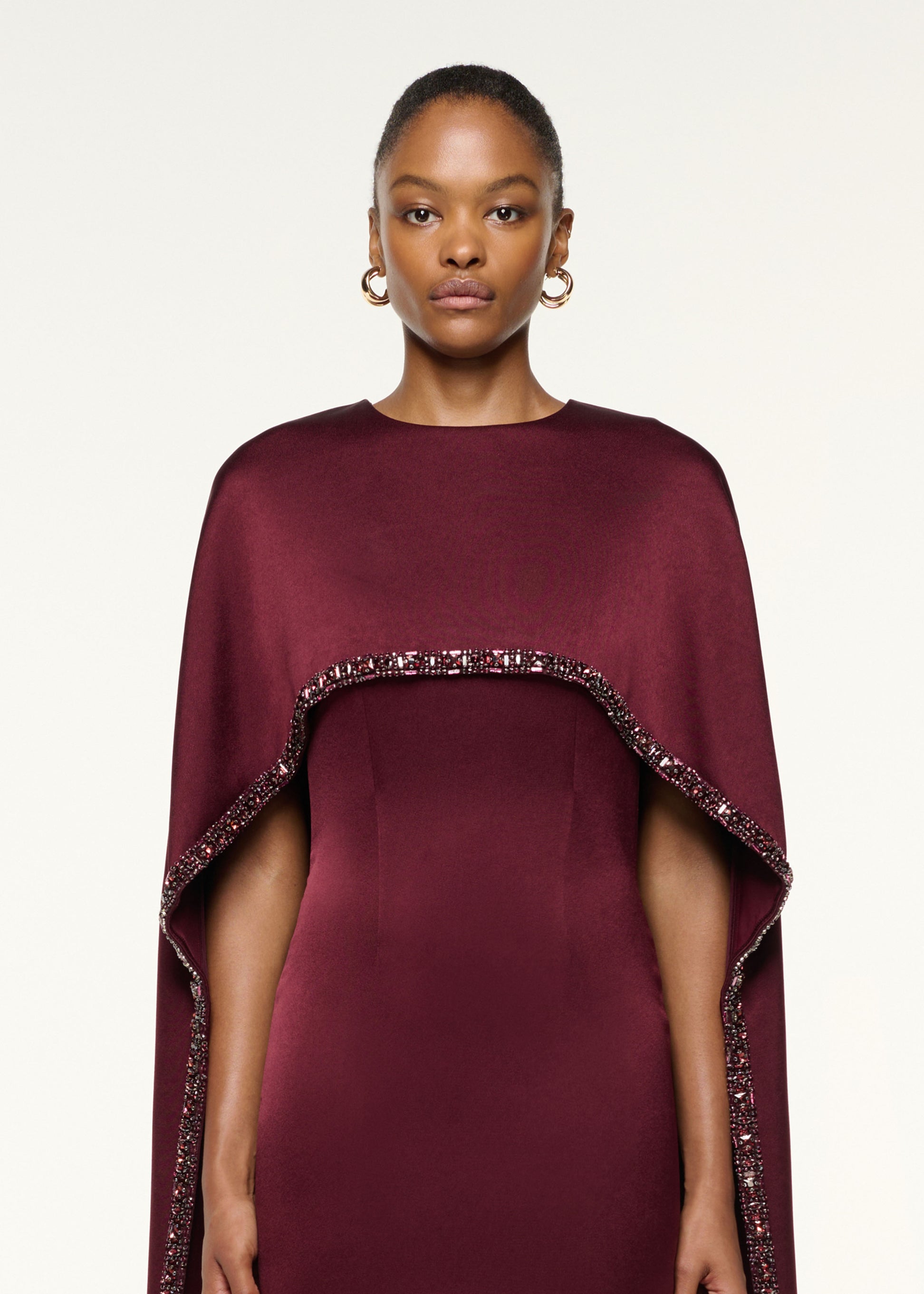 Close up of a model wearing the Crystal Trimmed Cape Midi Dress in Mulberry
