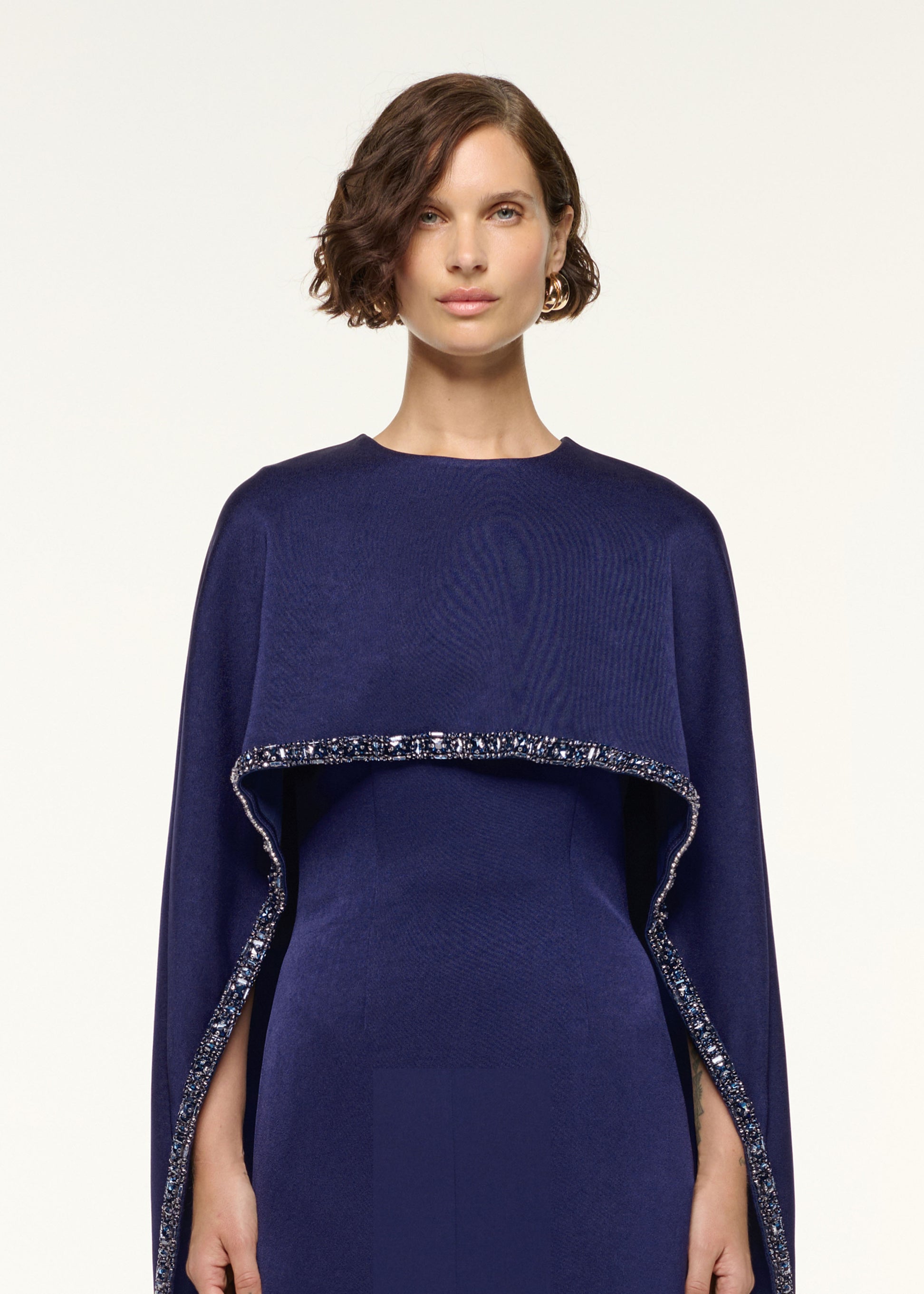 Close up of a model wearing the Crystal Trimmed Cape Mini Dress in Navy