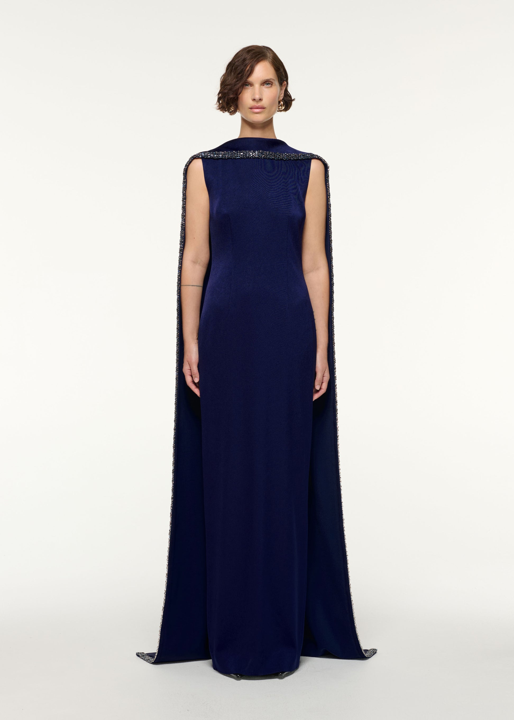 Front view of a model wearing the Crystal Trimmed Cape Gown in Navy