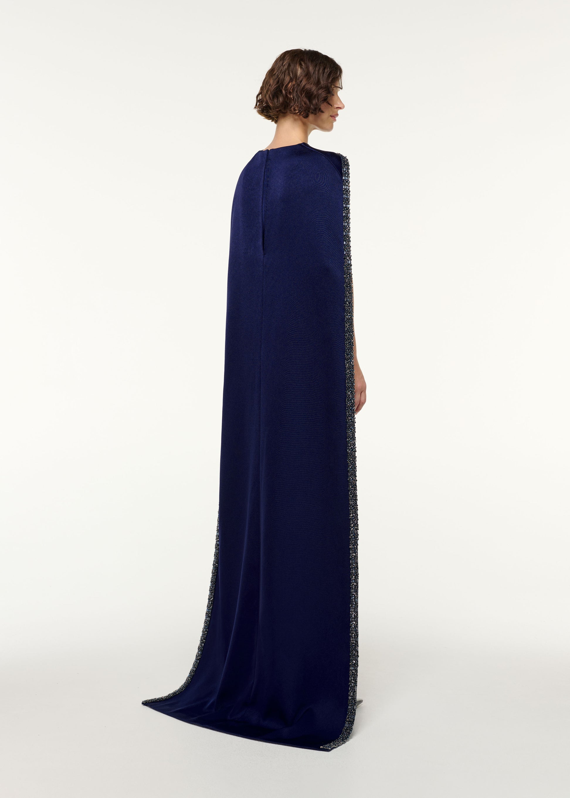 Back view of a model wearing the Crystal Trimmed Cape Gown in Navy