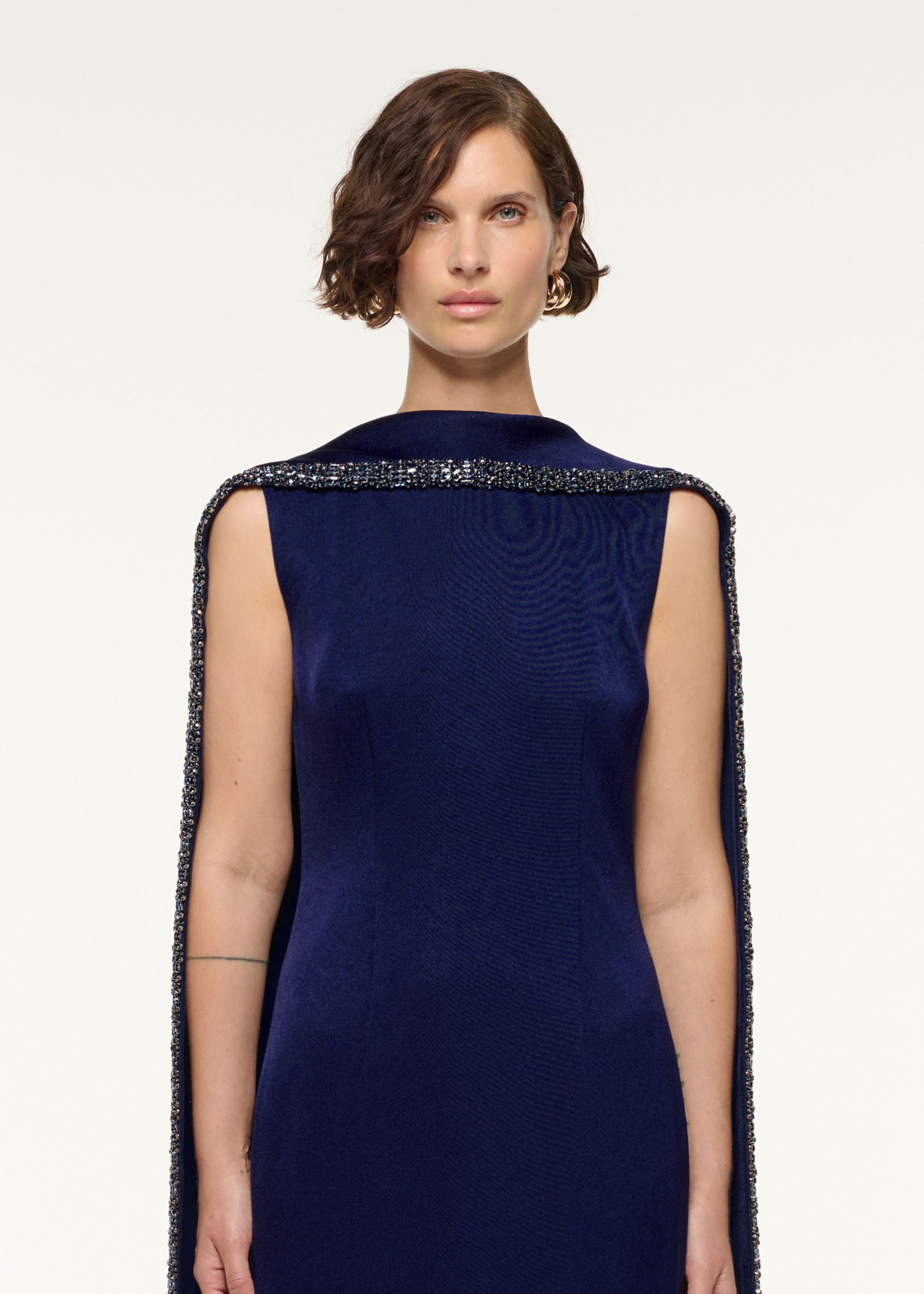 Close up of a model wearing the Crystal Trimmed Cape Gown in Navy