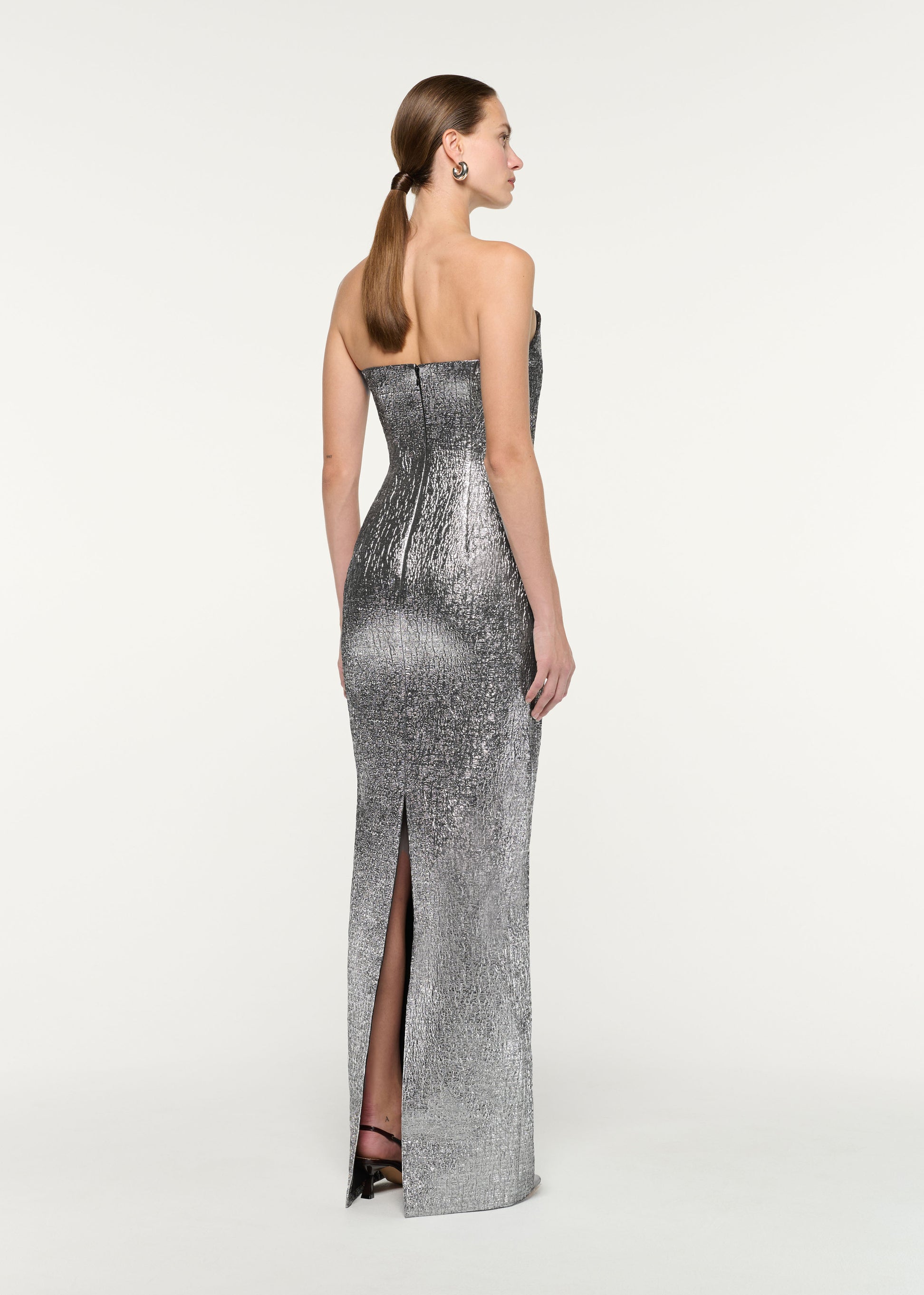 Back view of a model wearing the Pleated Strapless Metallic Jacquard Gown