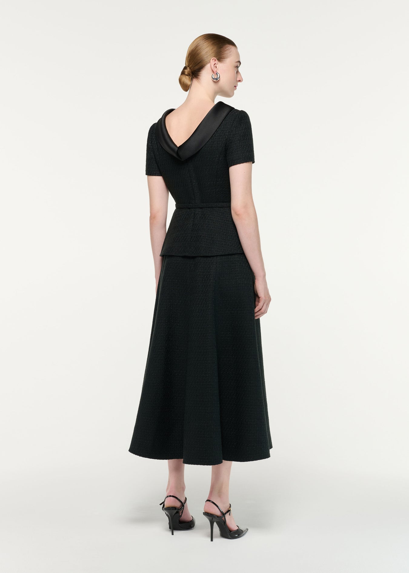 Back view of a model wearing the Collared Boucle Peplum Midi Dress