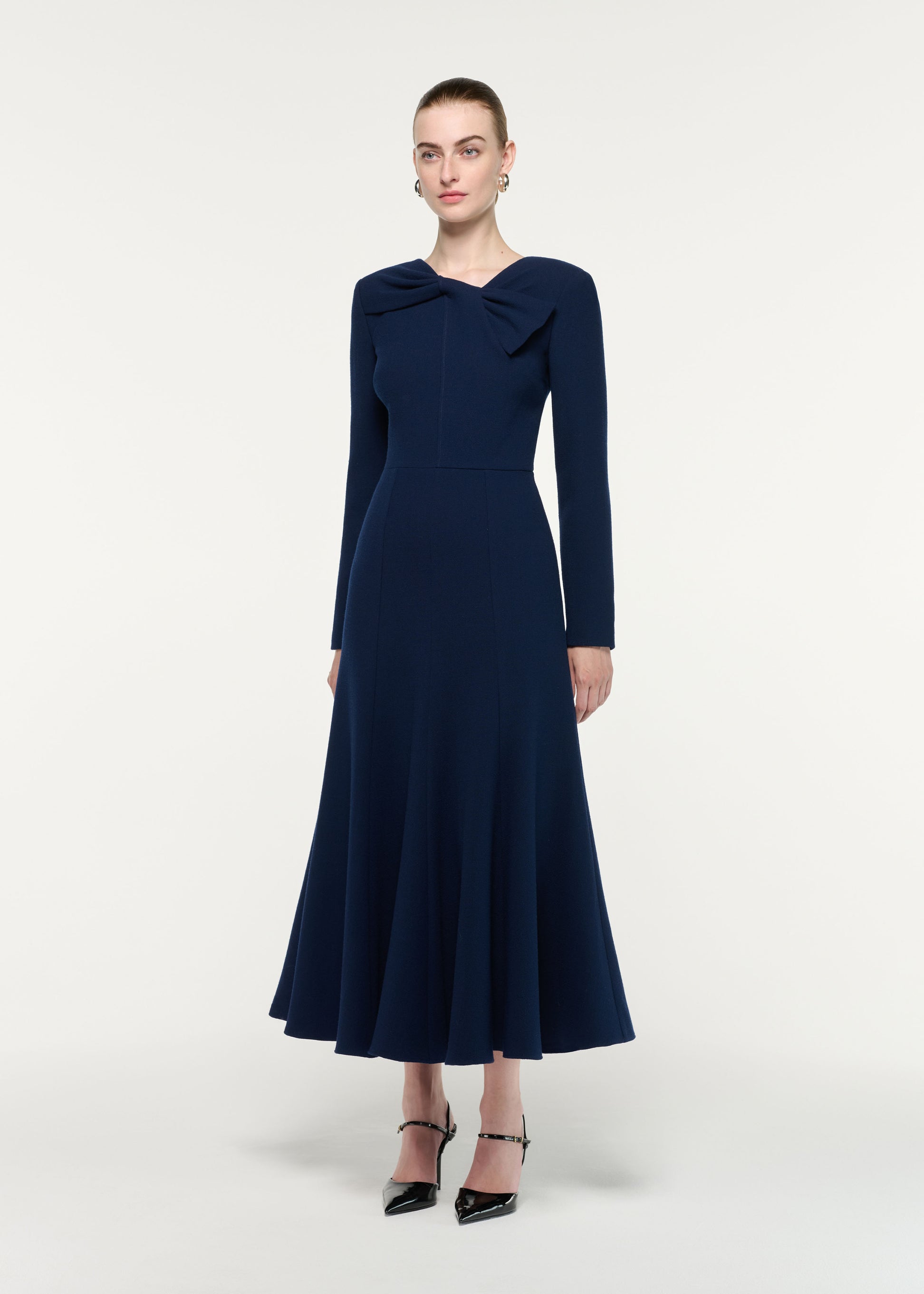 Side view of a model wearing the Asymmetric Bow Neck Wool Crepe Midi Dress