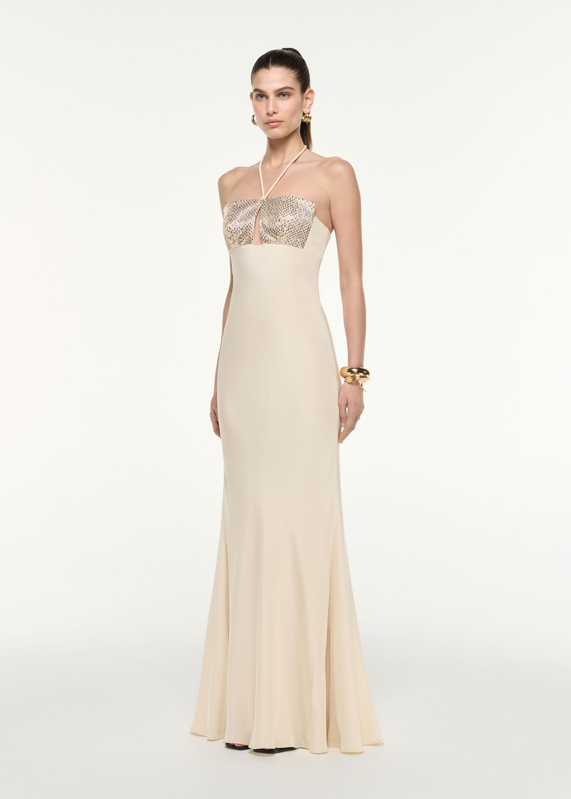 Side view of a model wearing the Diamante Halter Neck Silk Gown in Champagne