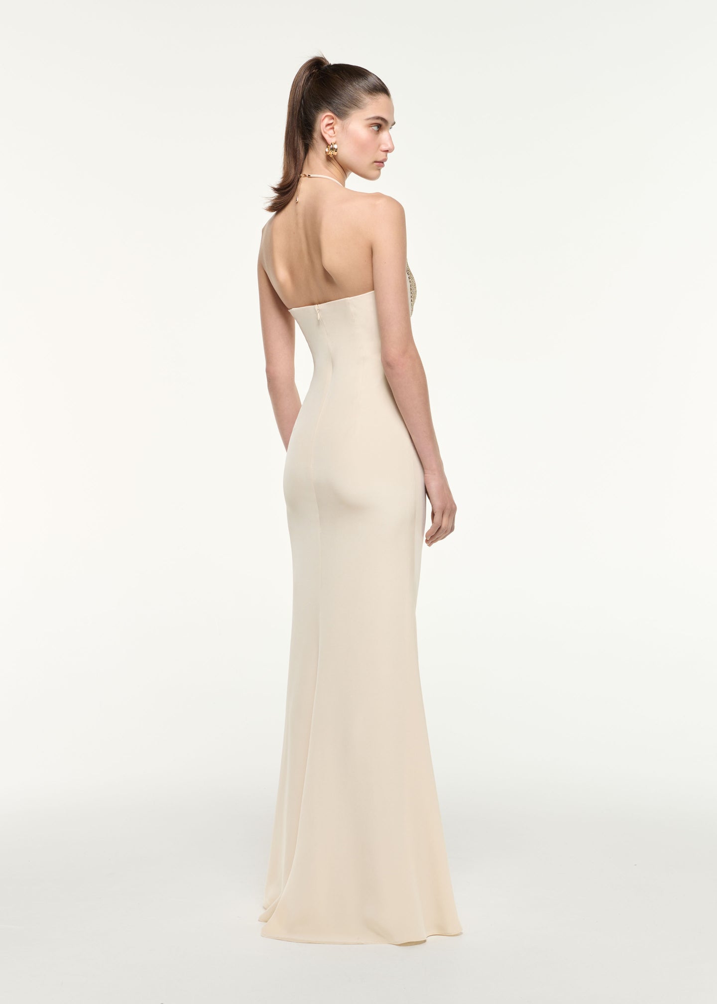 Back view of a model wearing the Diamante Halter Neck Silk Gown in Champagne
