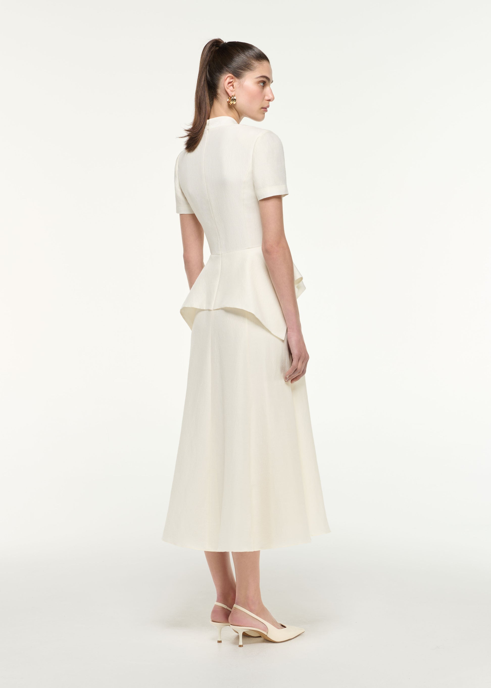 Back view of a model wearing the Silk Jacquard Peplum Midi Dress in Cream