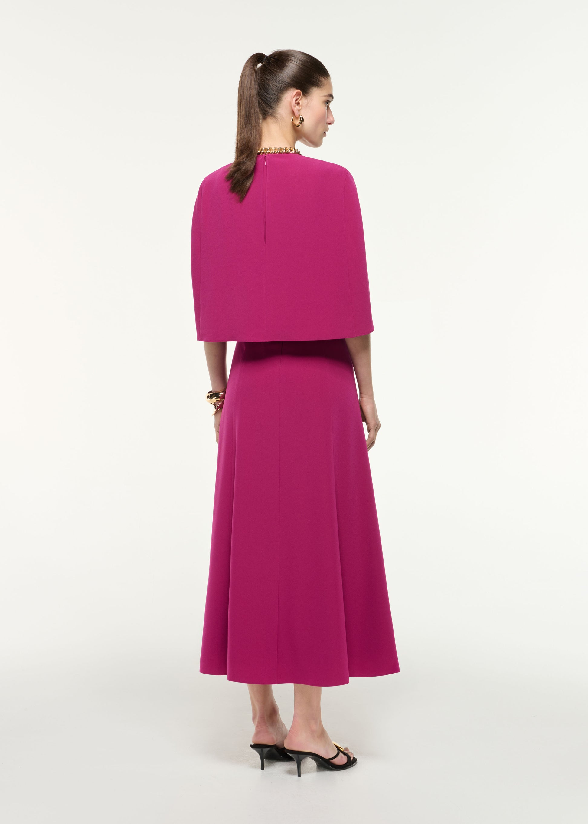 Back view of a model wearing the Satin Crepe Cape Midi Dress in Dark Pink