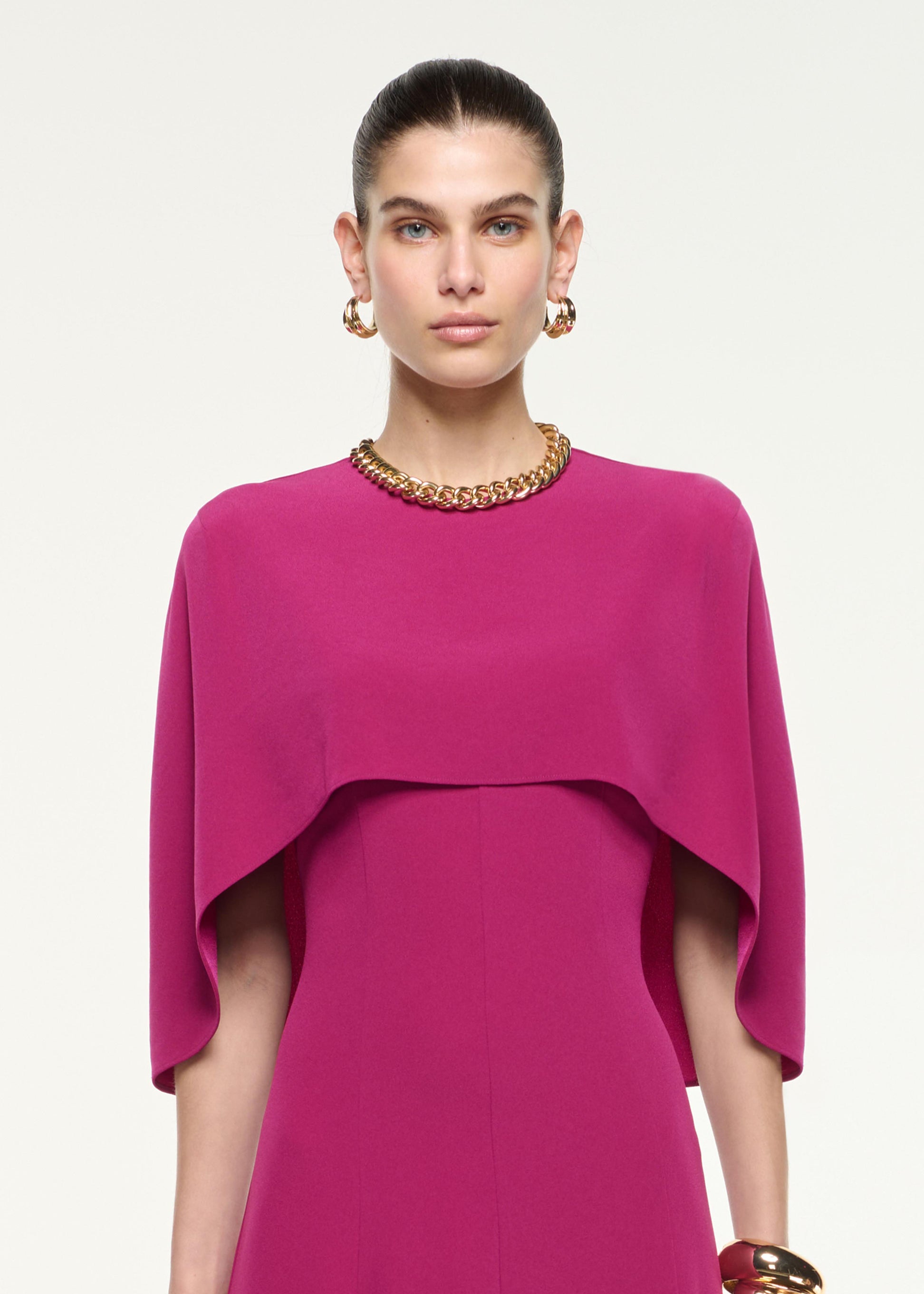 Close up of a model wearing the Satin Crepe Cape Midi Dress in Dark Pink