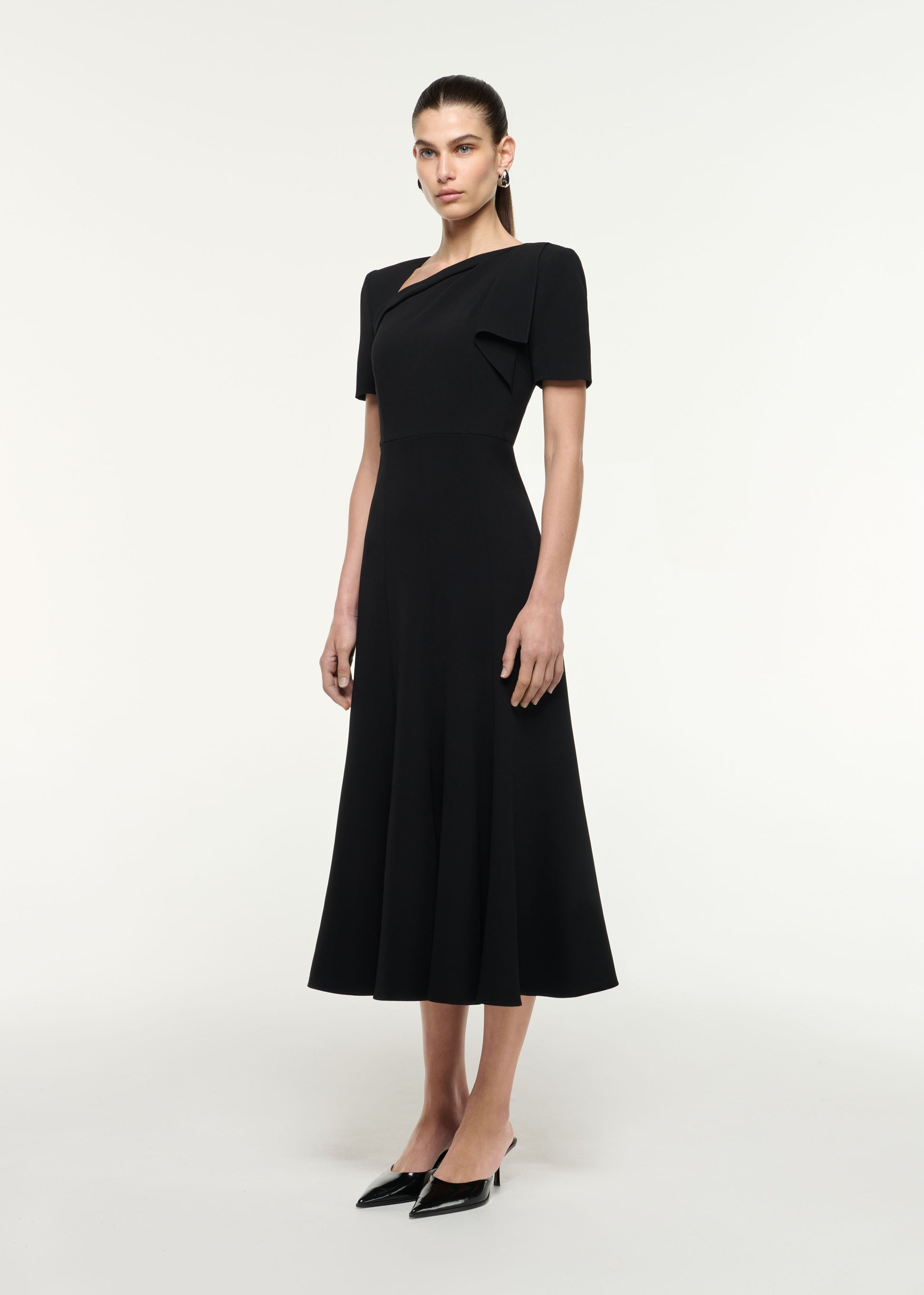 Side view of a model wearing the Shoulder Drape Midi Dress in Black